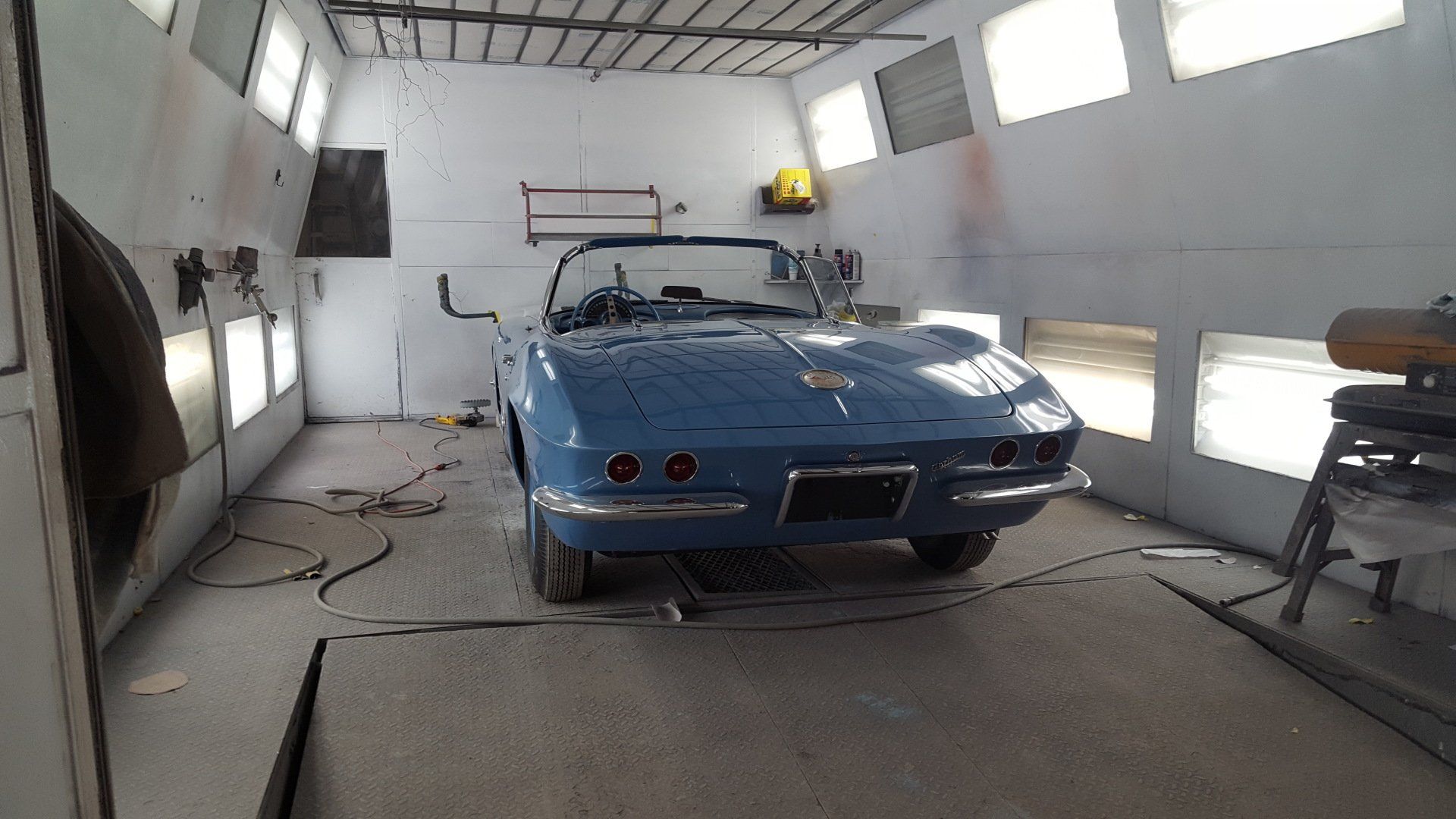 Blue convertible car inside a paint booth, preparing for a paint job.