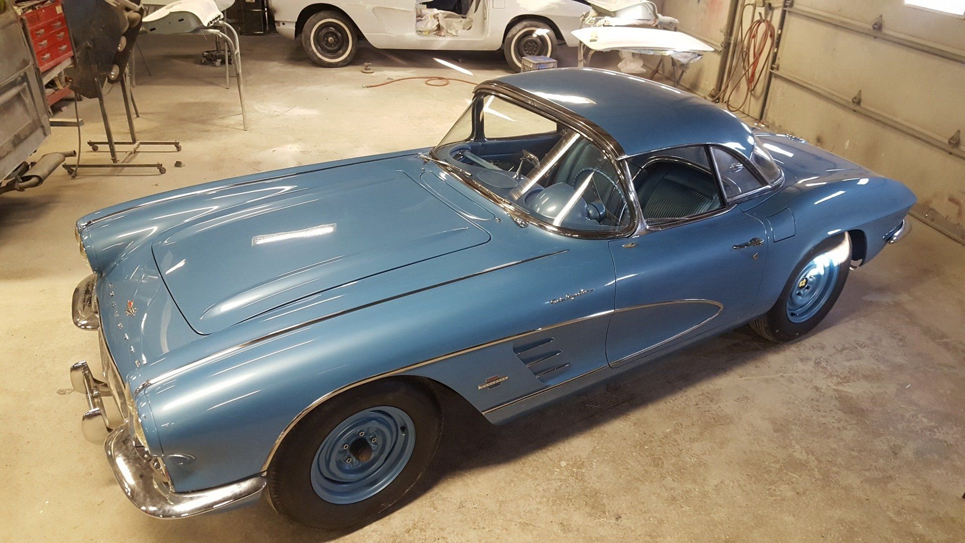 Blue vintage Corvette coupe in a garage.