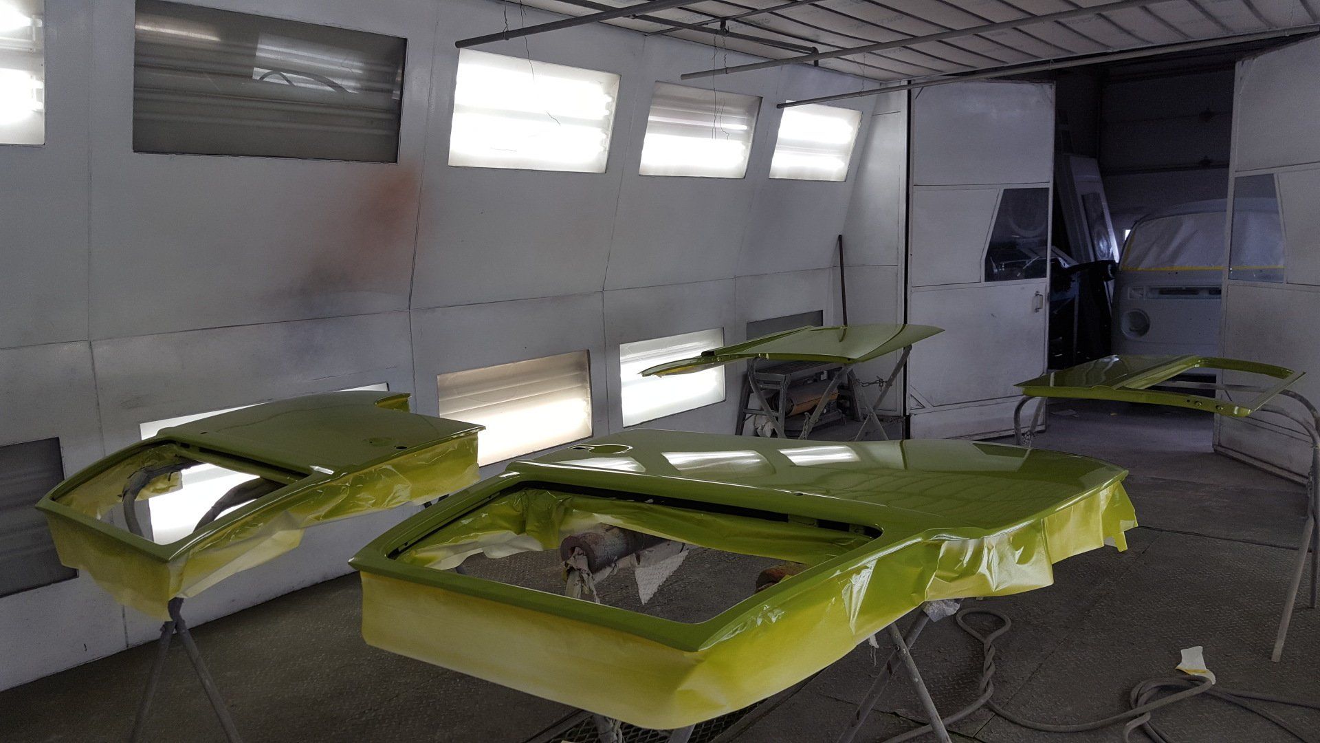 Green car parts in a paint booth, ready for final coat.