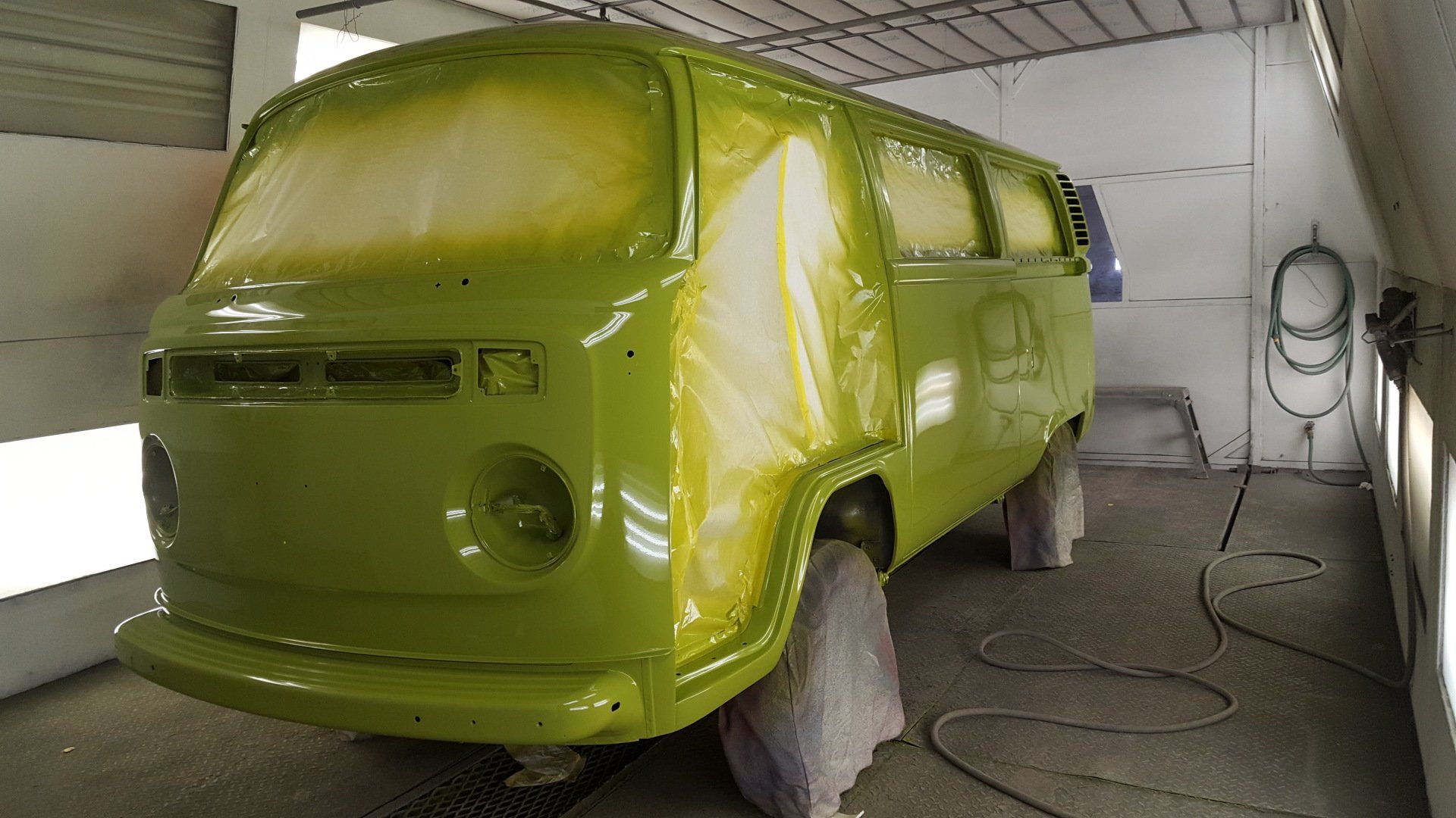 Green Volkswagen van in a paint booth being painted green.