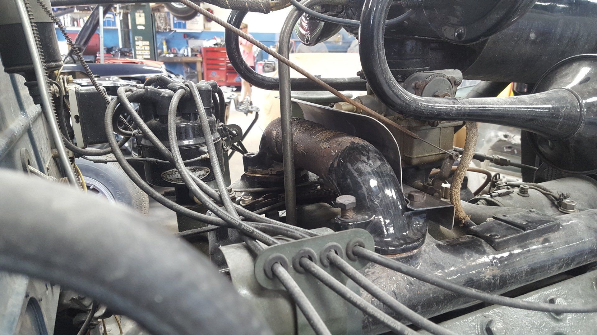 Engine compartment of a vehicle, showing various components, including hoses, wires, and air intake.