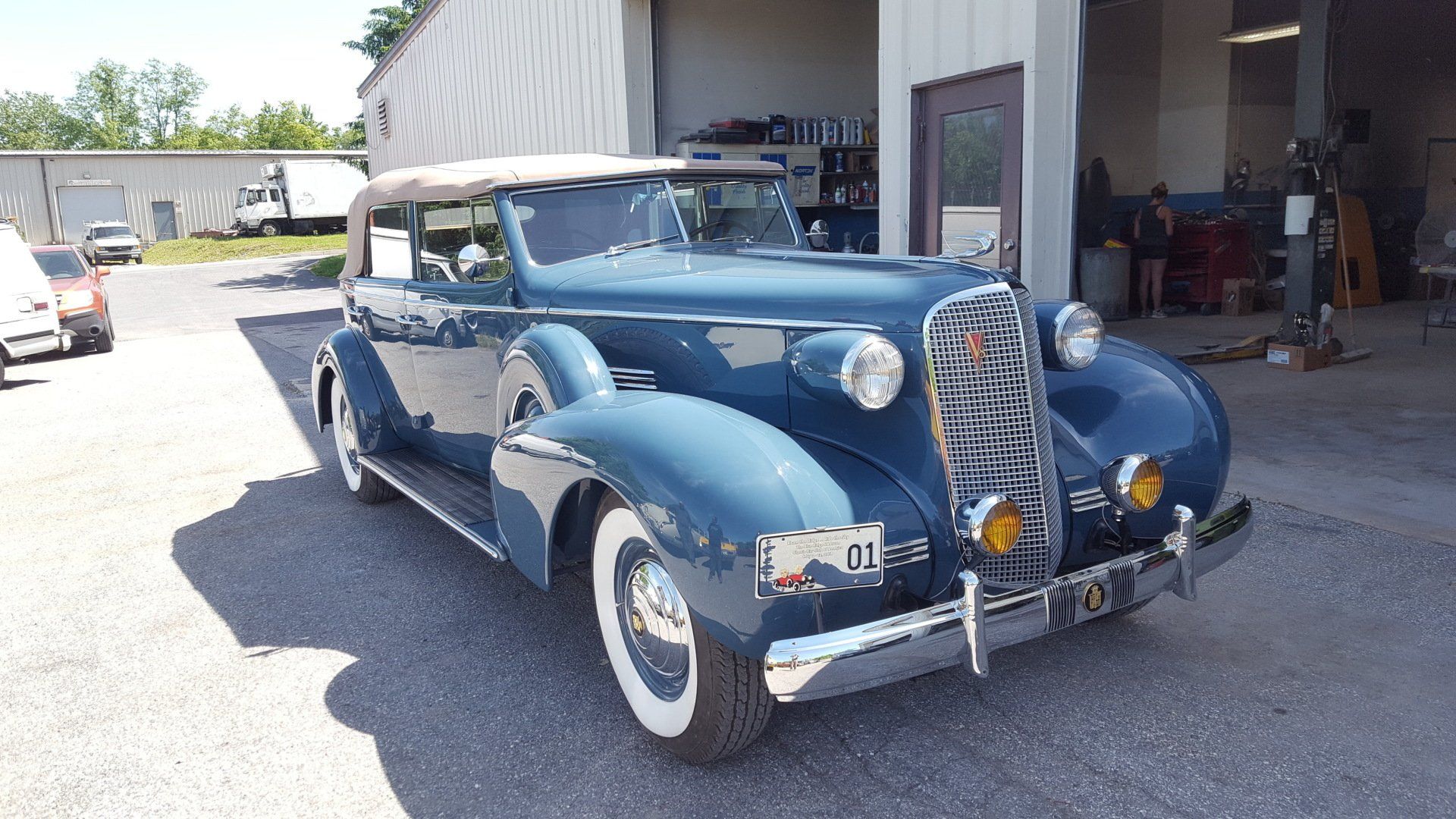 Blue vintage convertible car parked outside a garage.