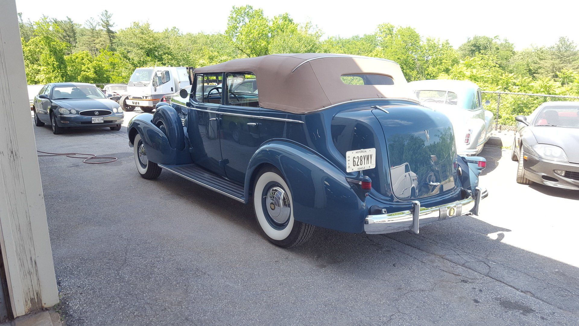 Blue vintage convertible car with a tan roof parked outdoors.