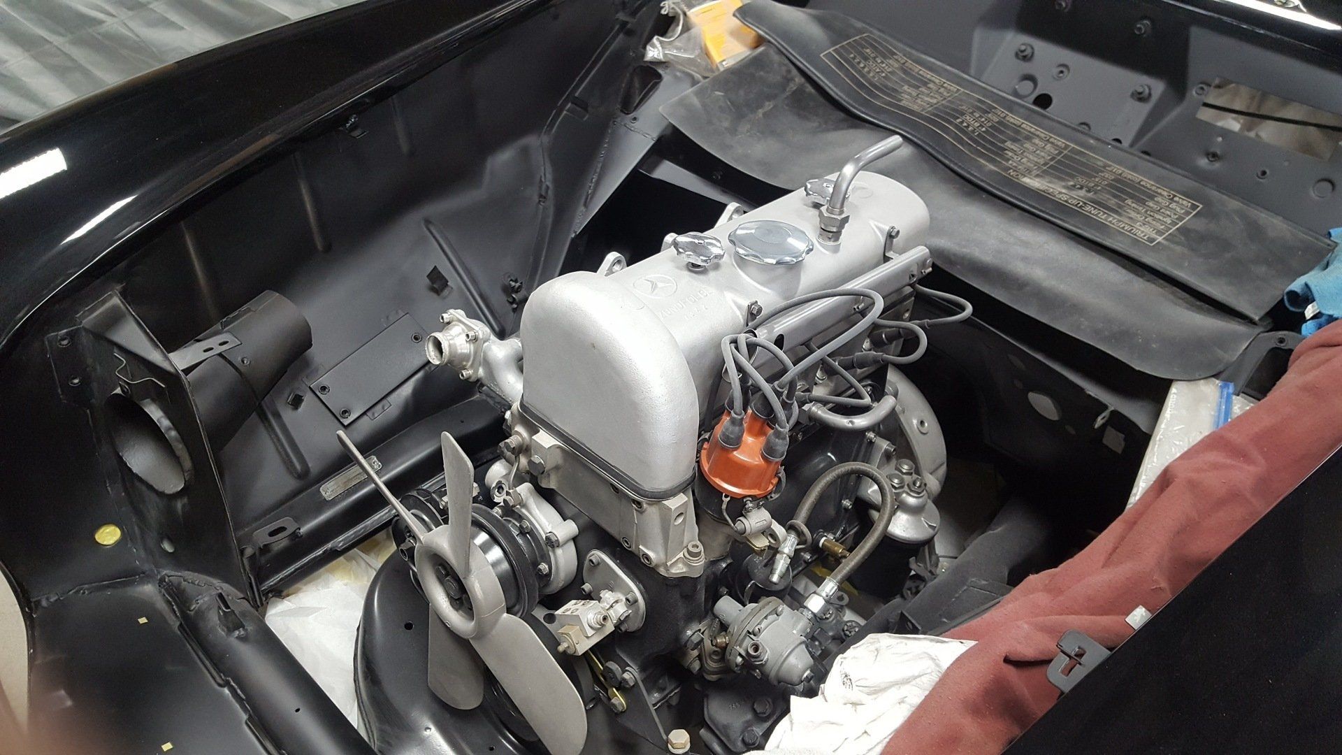 Black car engine compartment with silver engine, fan, and wiring.