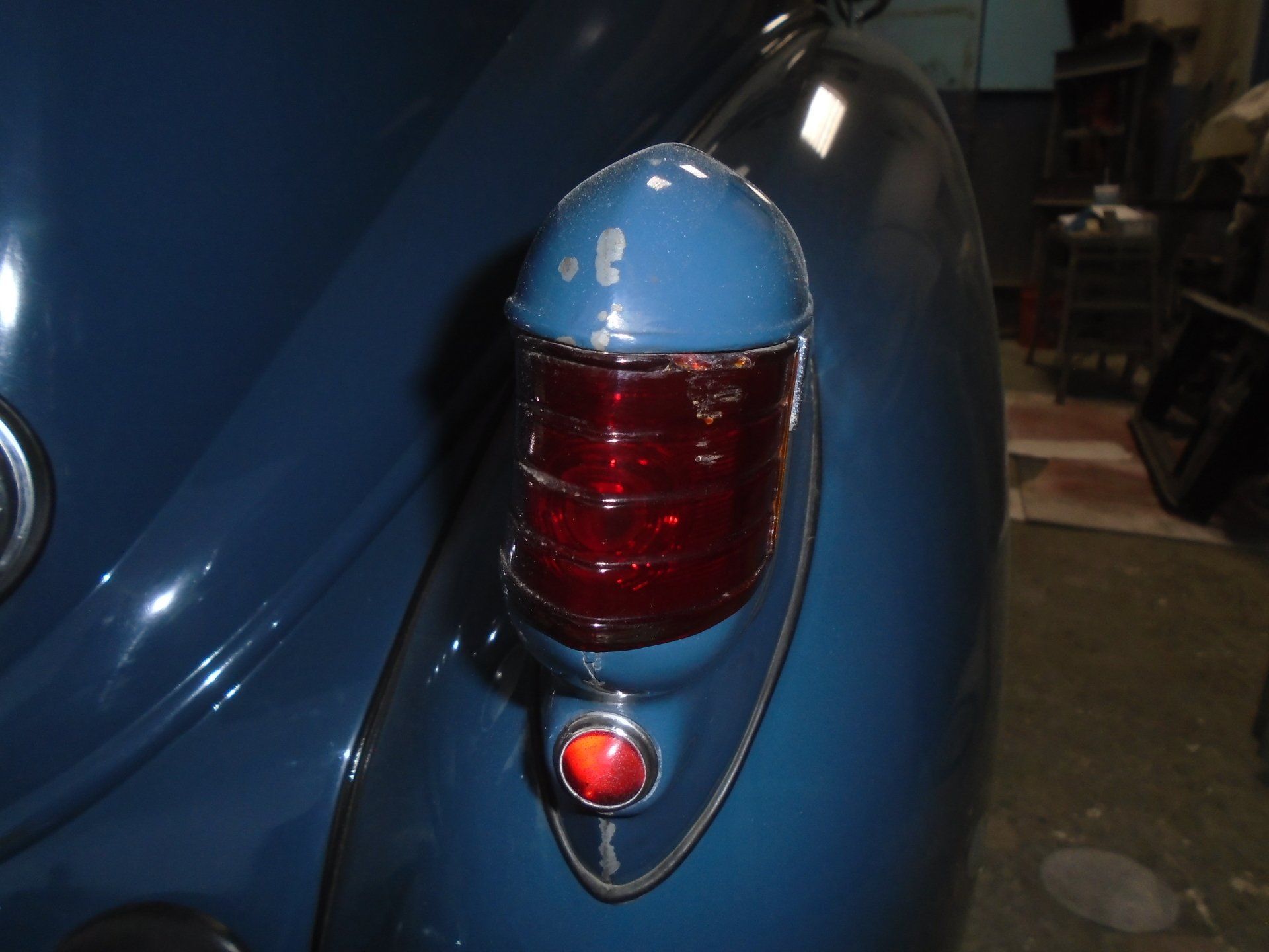 Blue car taillight with a red lens and a red reflector below it.