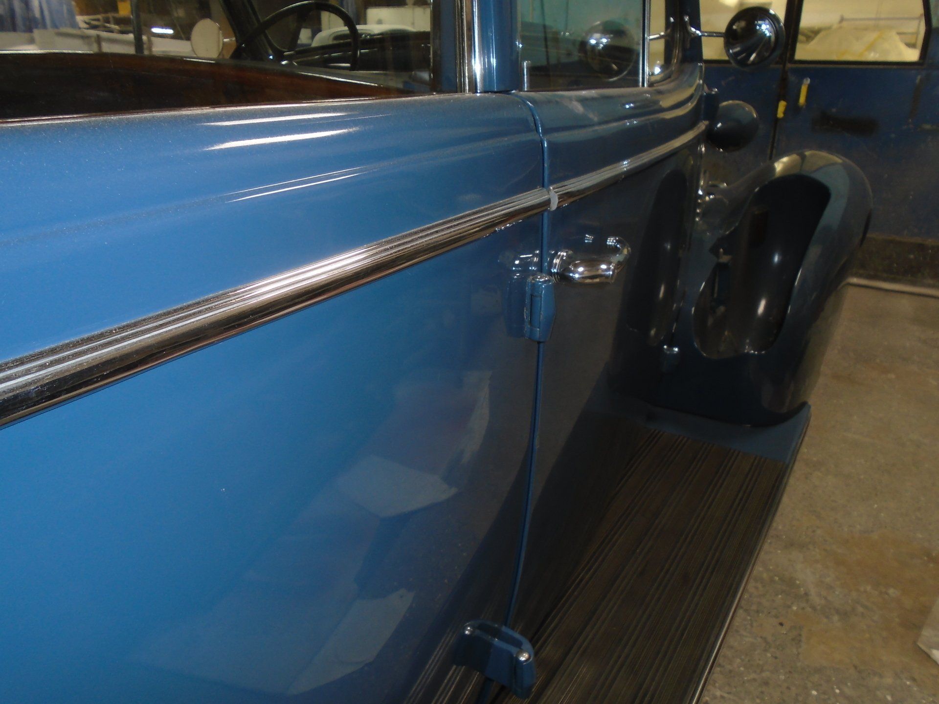 Blue classic car door with chrome trim and black fender.