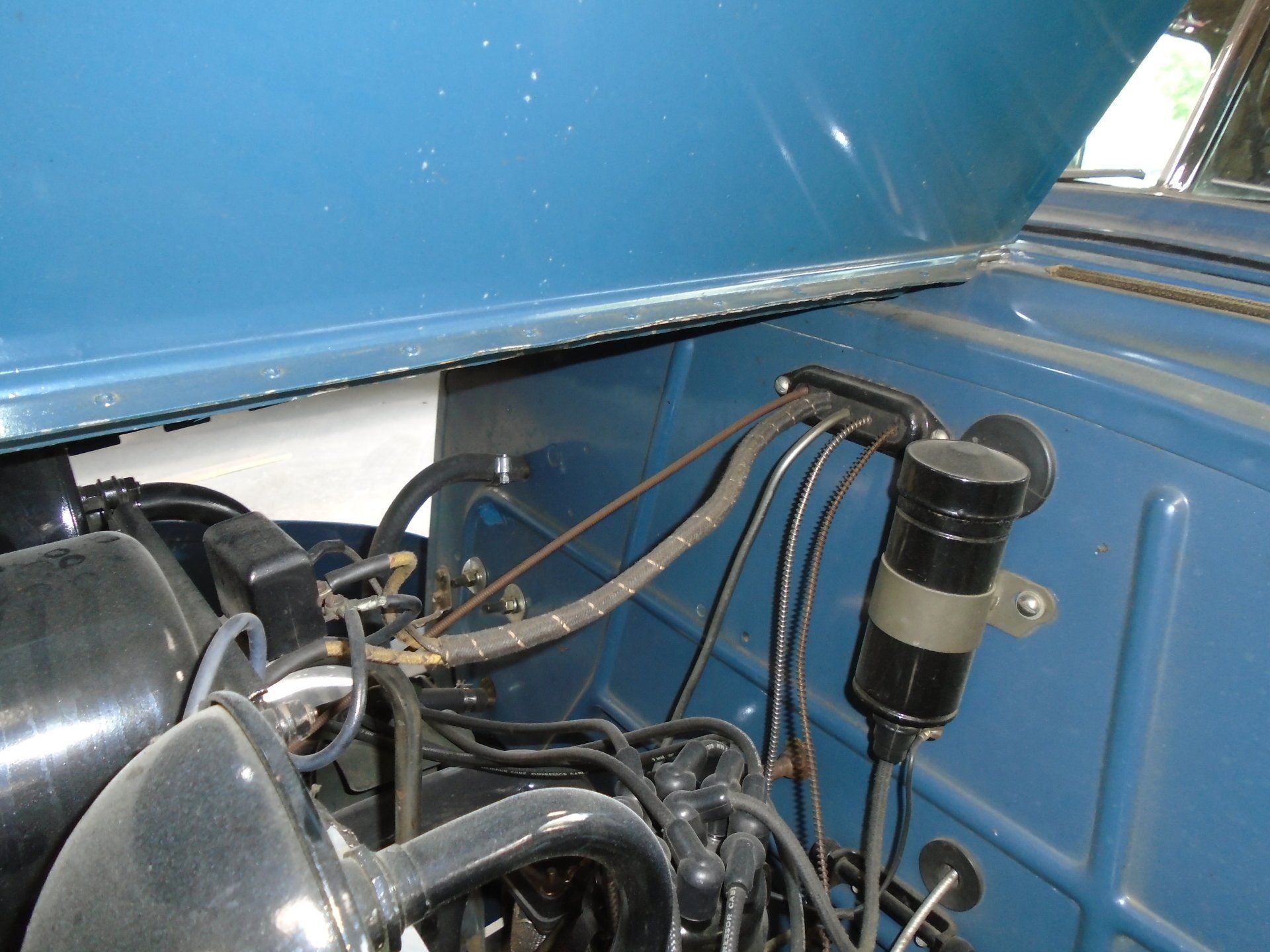 Blue car engine bay with ignition coil and wiring.