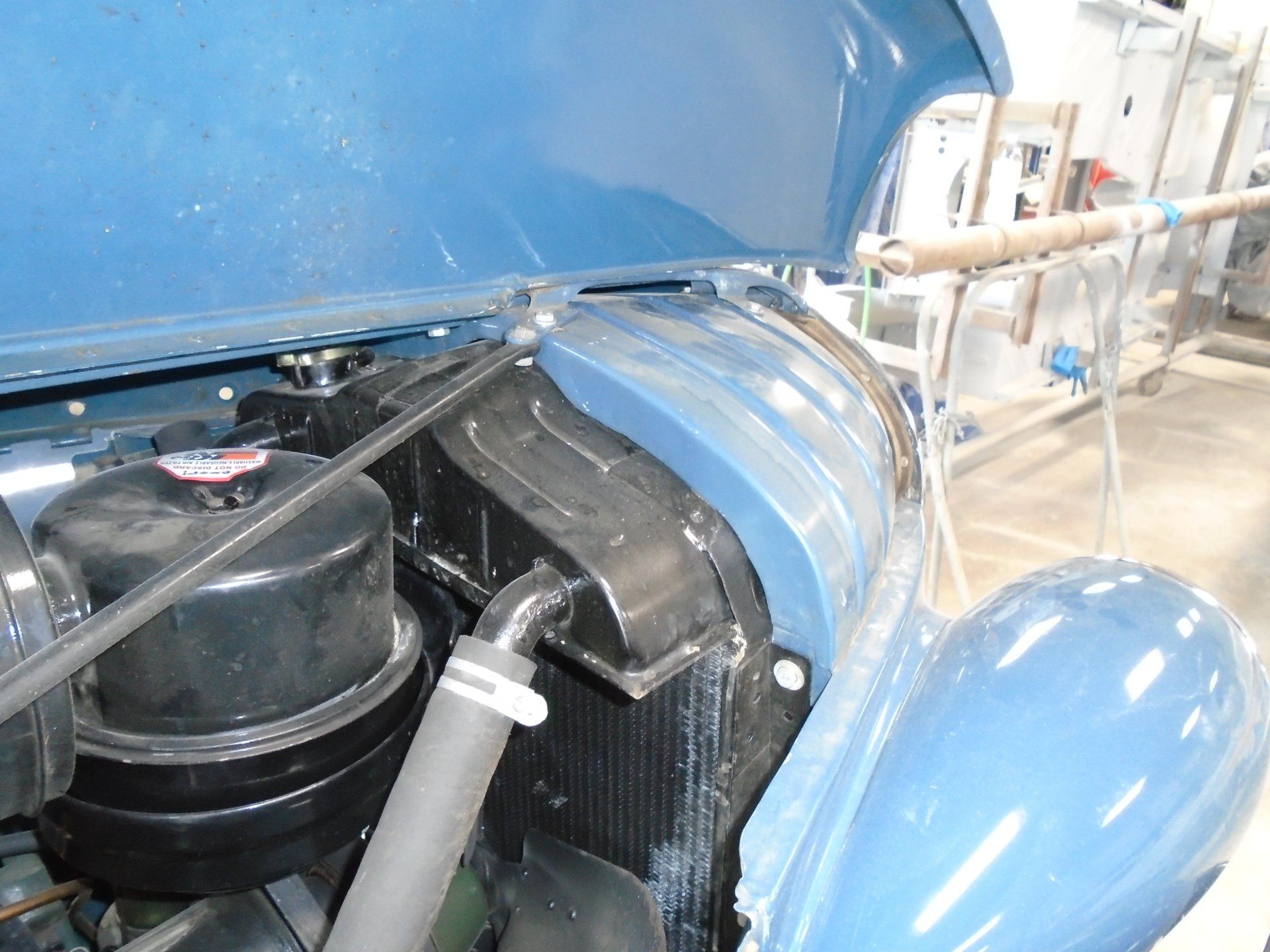 Blue car engine compartment, black components, radiator, air filter, and open hood.