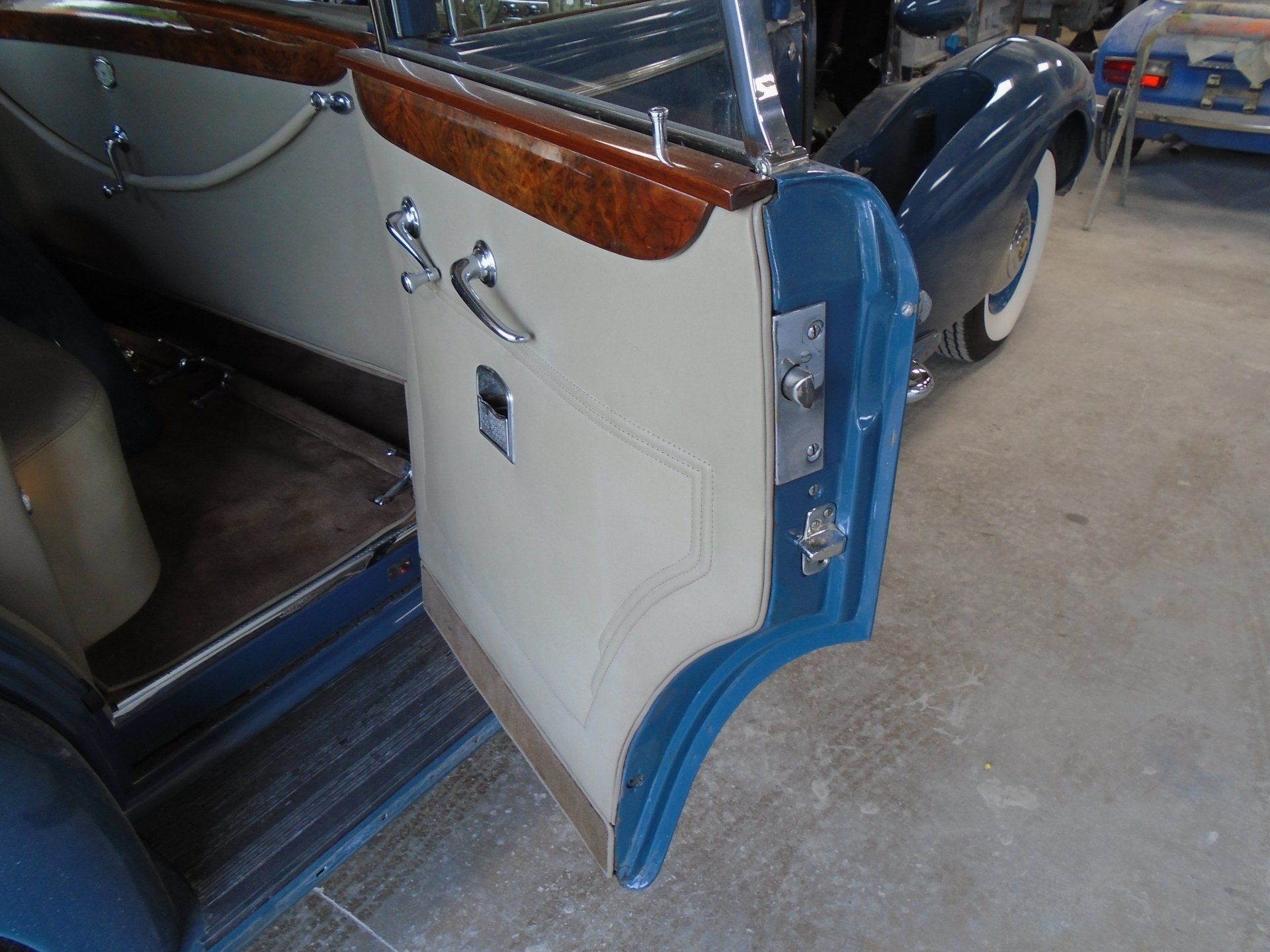 Open blue car door with cream-colored interior and wood trim.