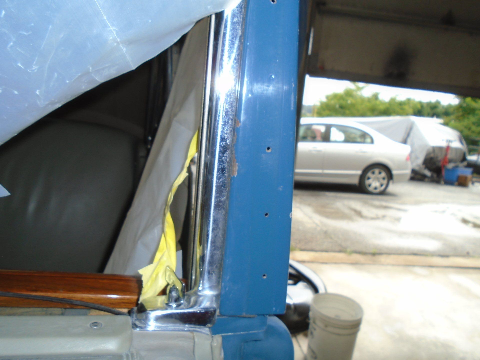 Blue and chrome car door frame, partially open, in a garage.
