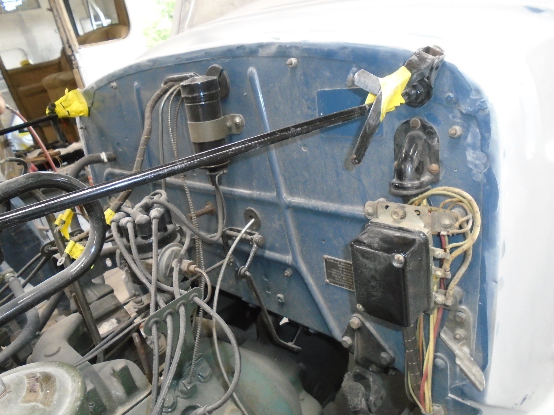 Blue engine bay of a vintage vehicle with various wires and components visible.