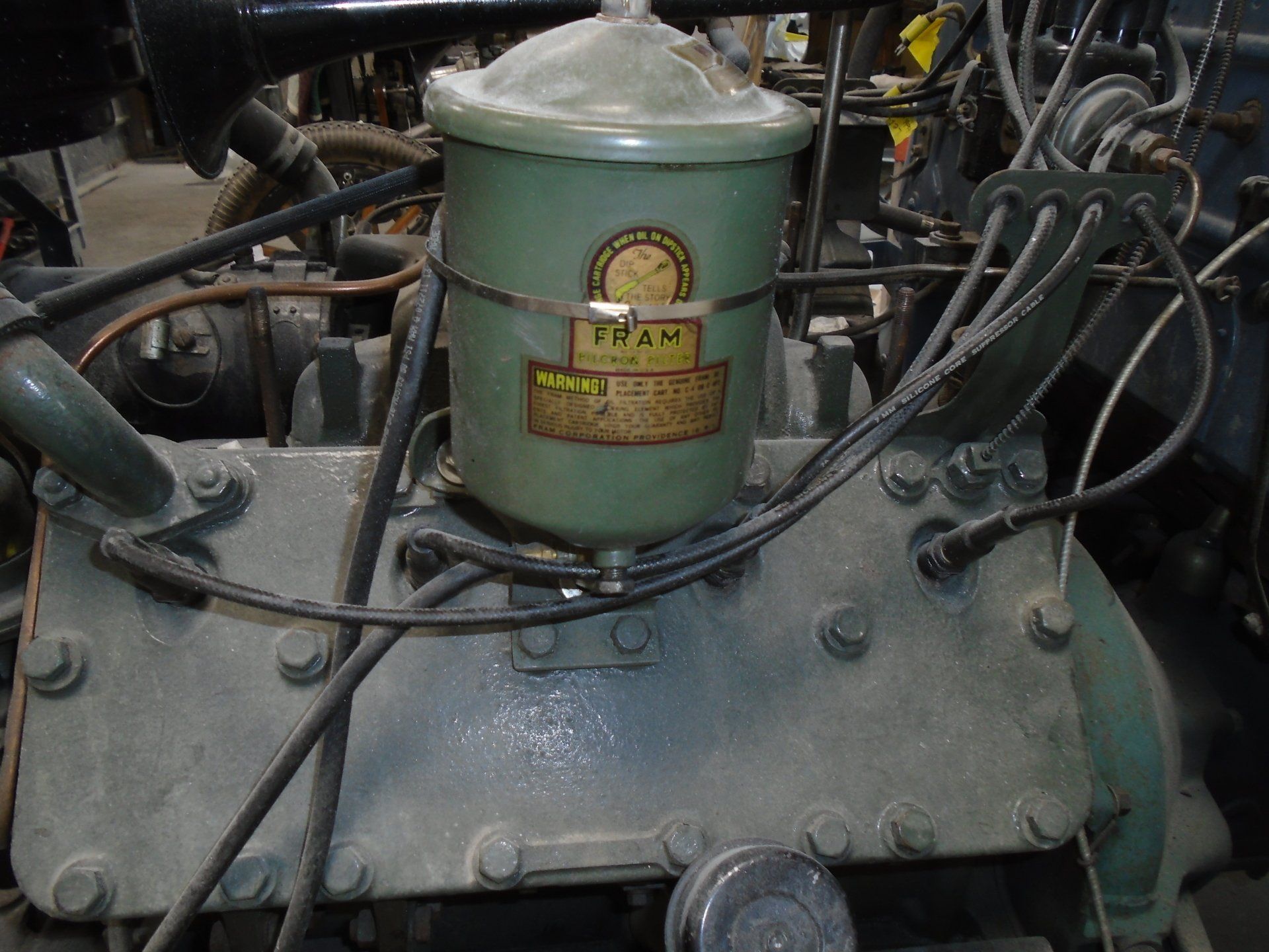 Green Fram oil filter on a vintage car engine.