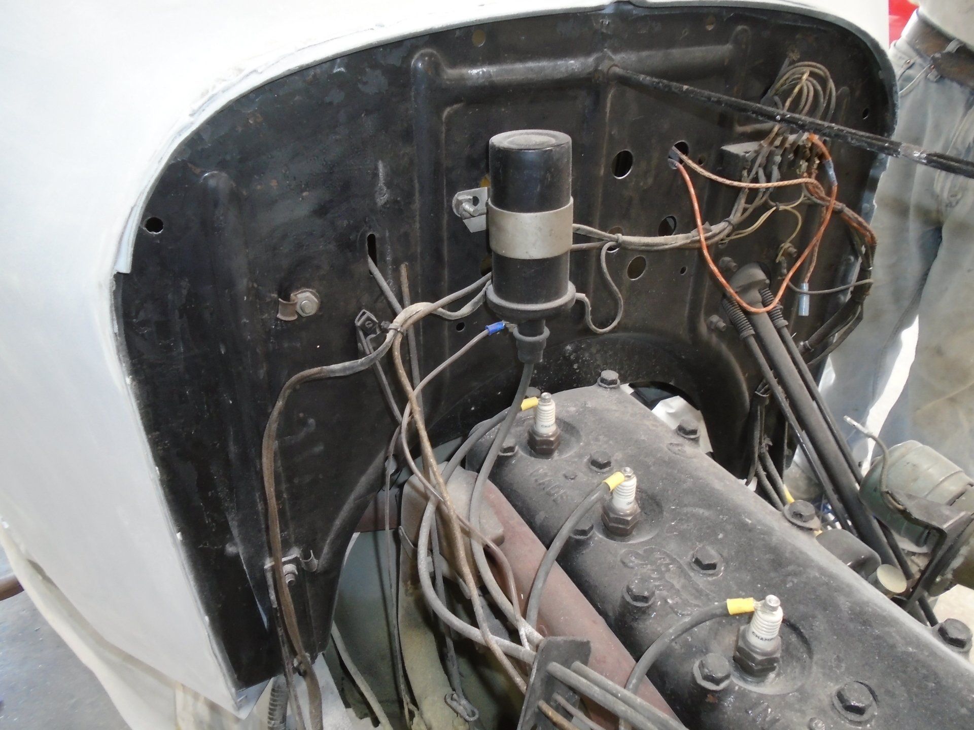 Black car engine bay with wires, coil, and spark plugs.