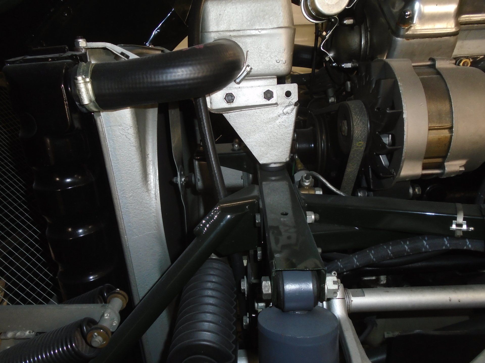 Engine components of a car, including a black hose, radiator, and alternator.