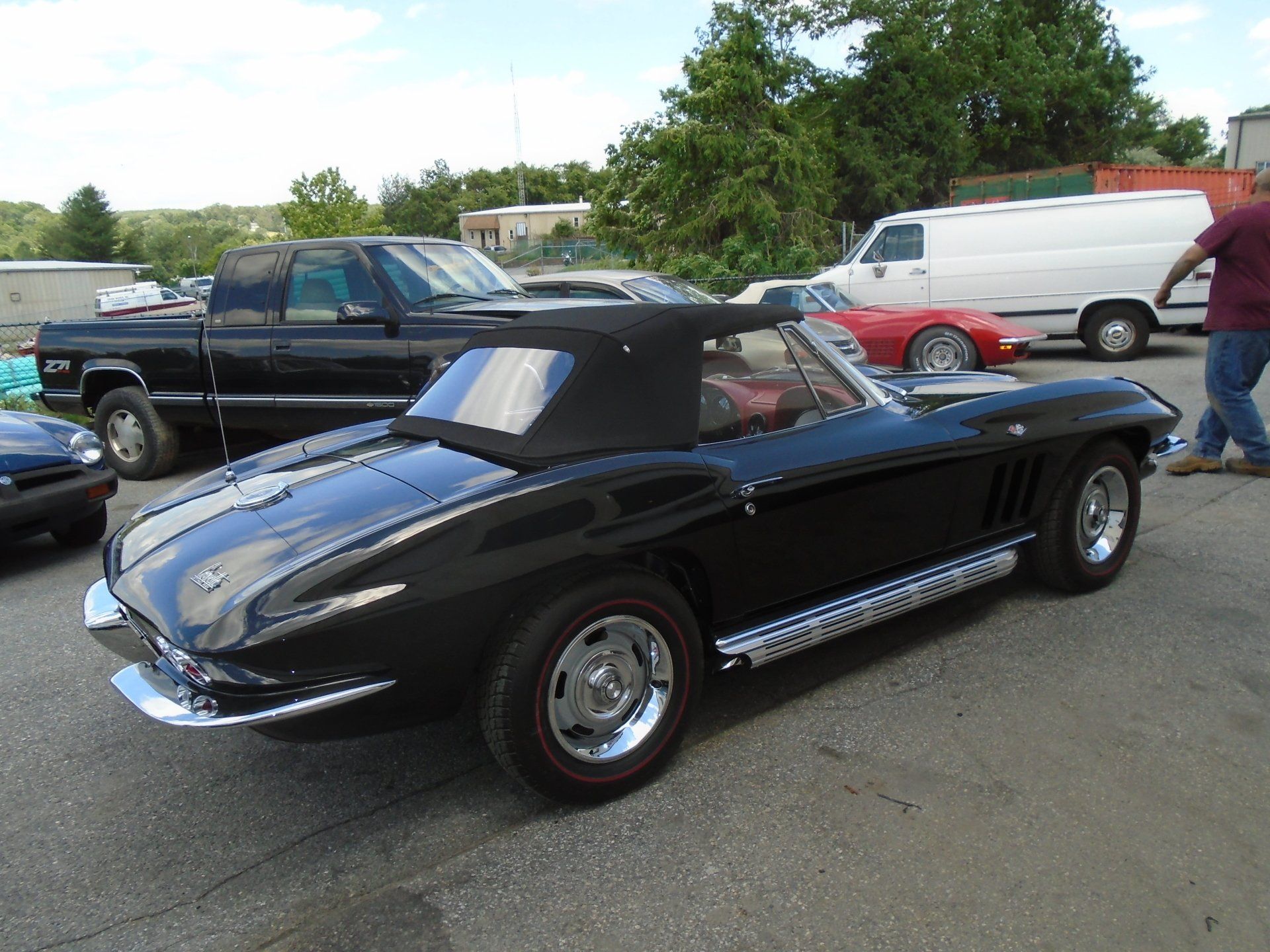 Black convertible classic car with a black top in a parking lot.