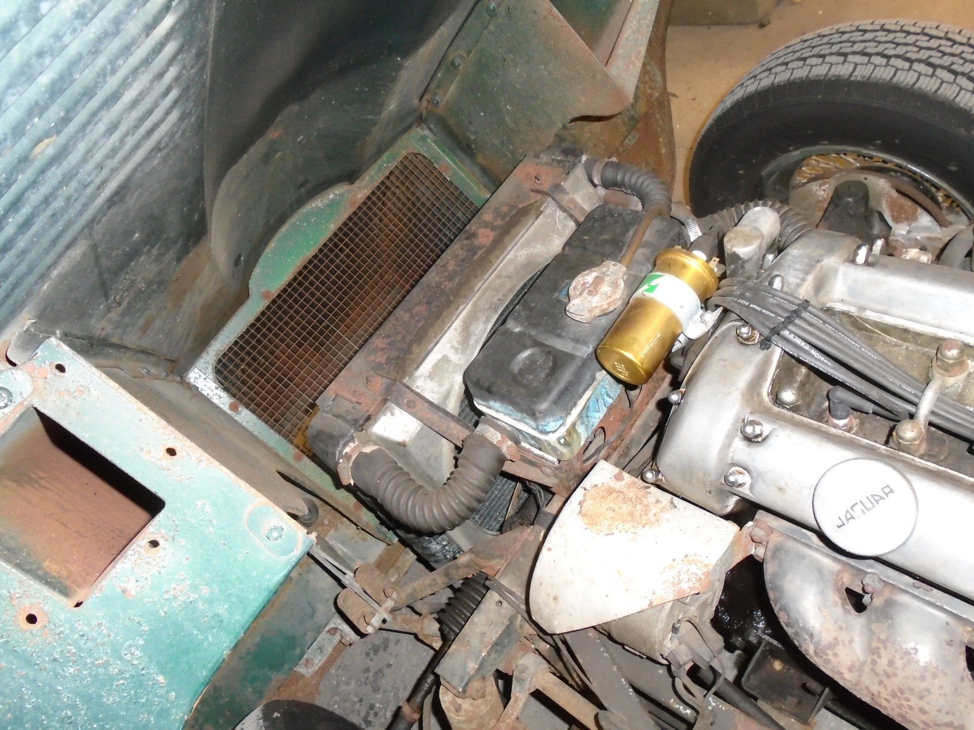 Engine compartment of a classic green car; radiator, engine components visible.