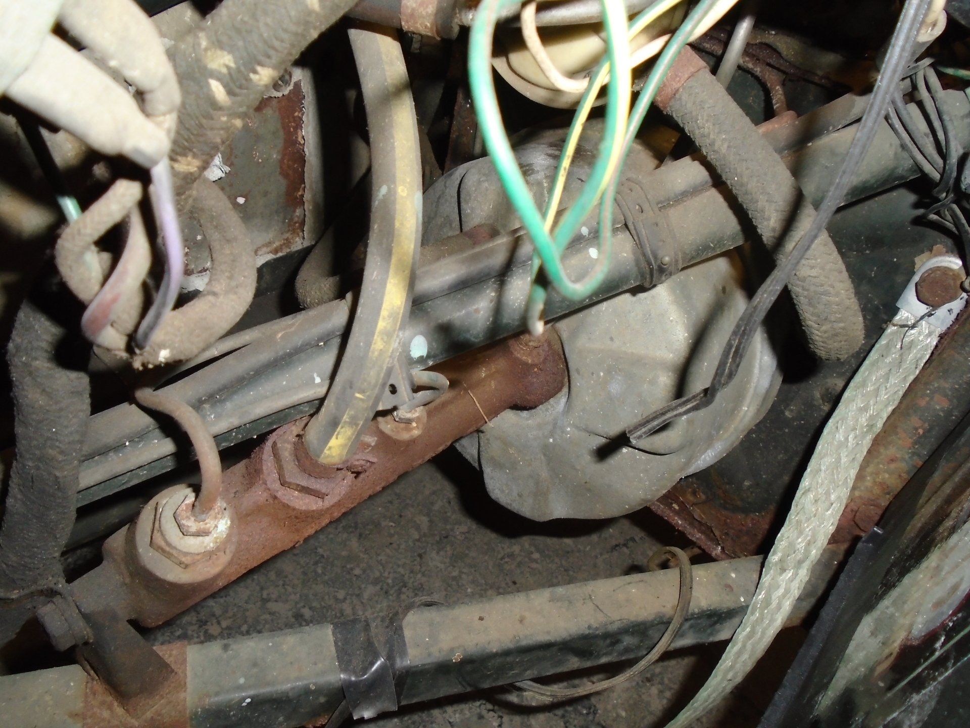 Rusty car brake components with wires and tubes.
