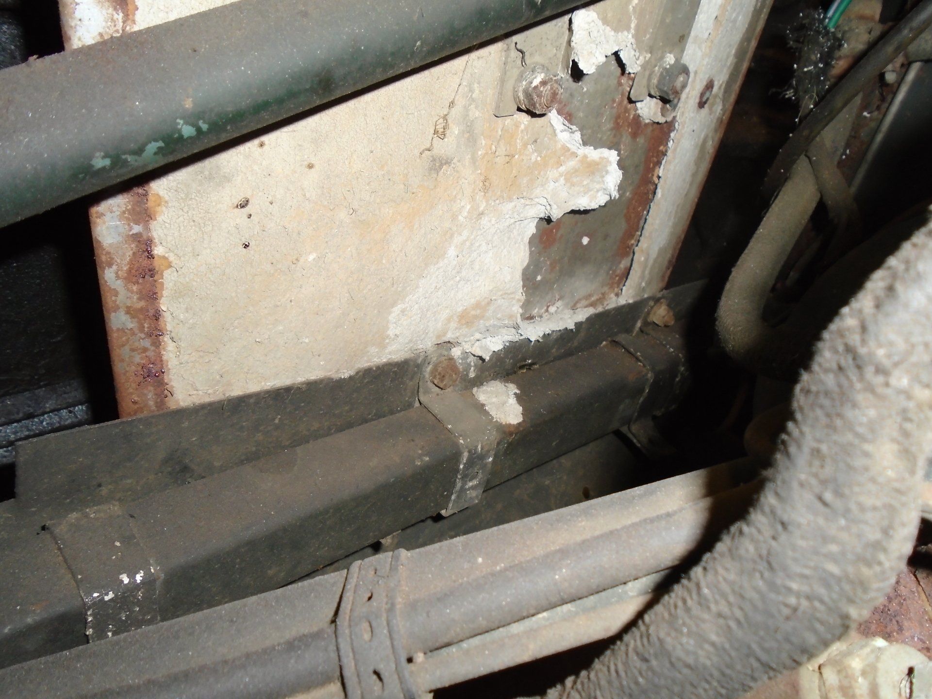 Rusty metal and pipes with concrete and insulation.