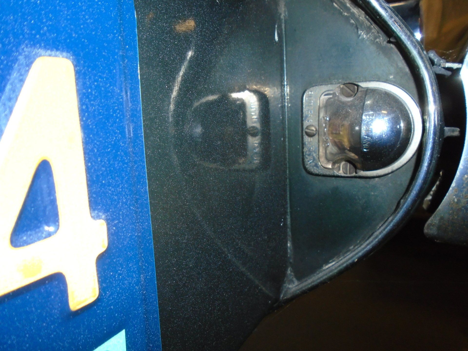 Green car fender with a headlight and a small, rectangular light next to it.