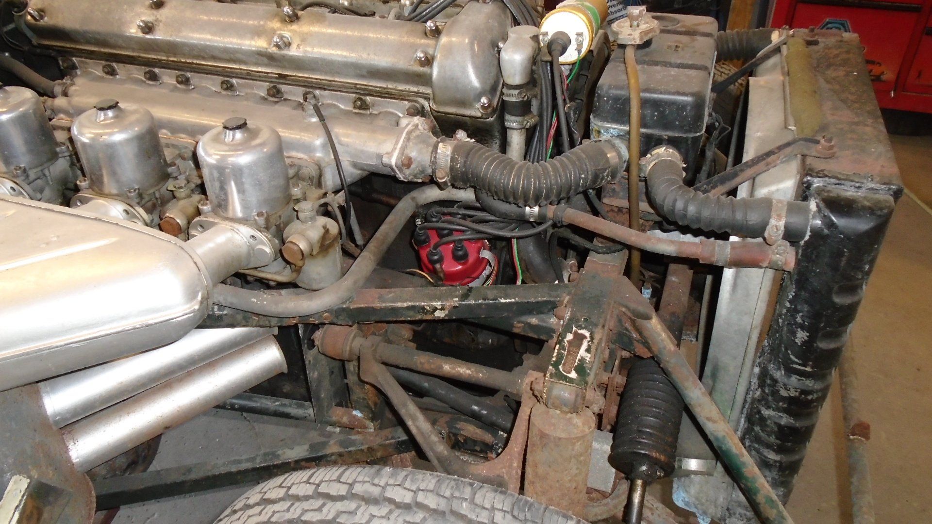 Engine bay of a classic car with engine, radiator, and front suspension visible.