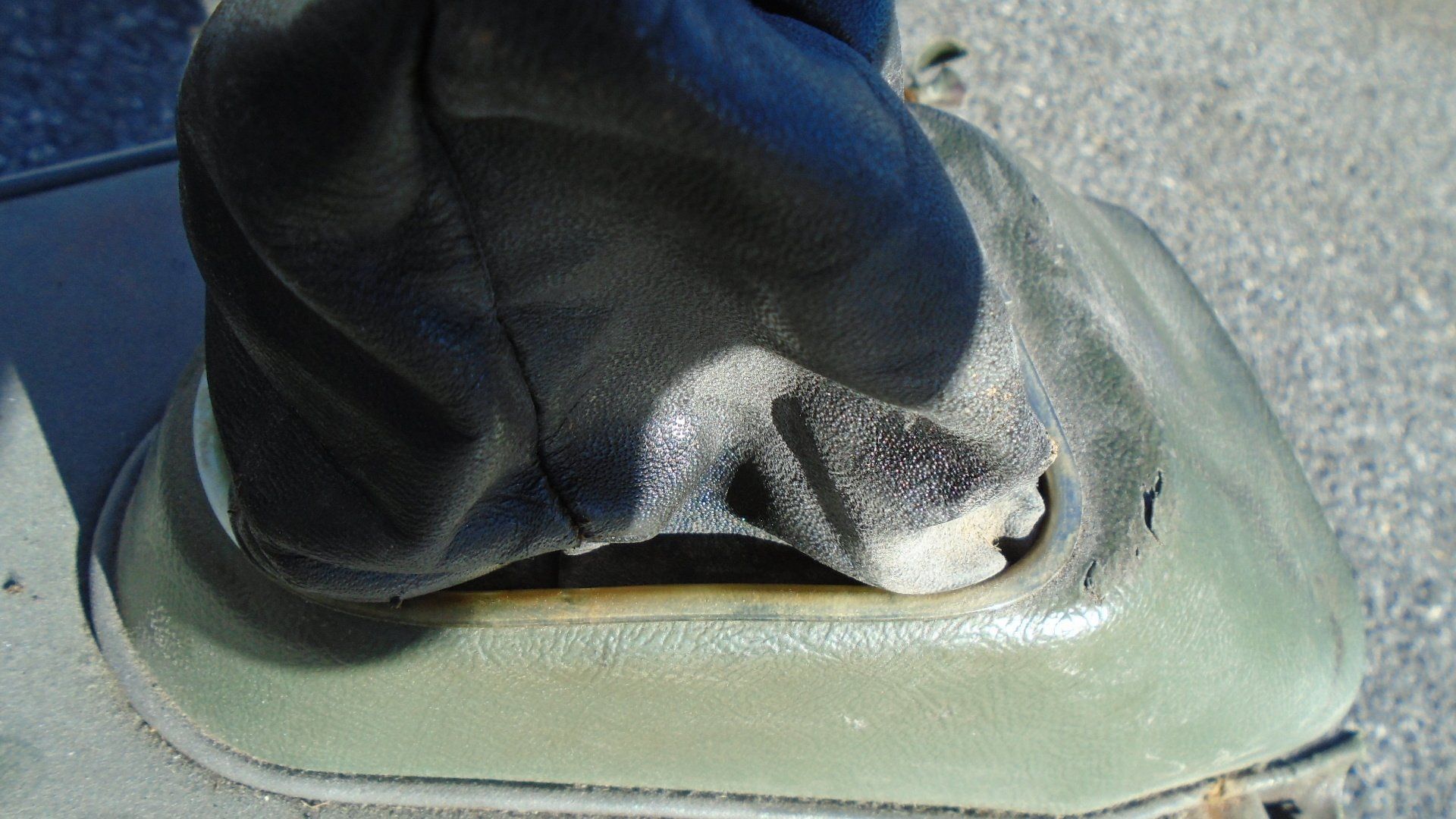 Green plastic shift boot base with a black shift lever boot.