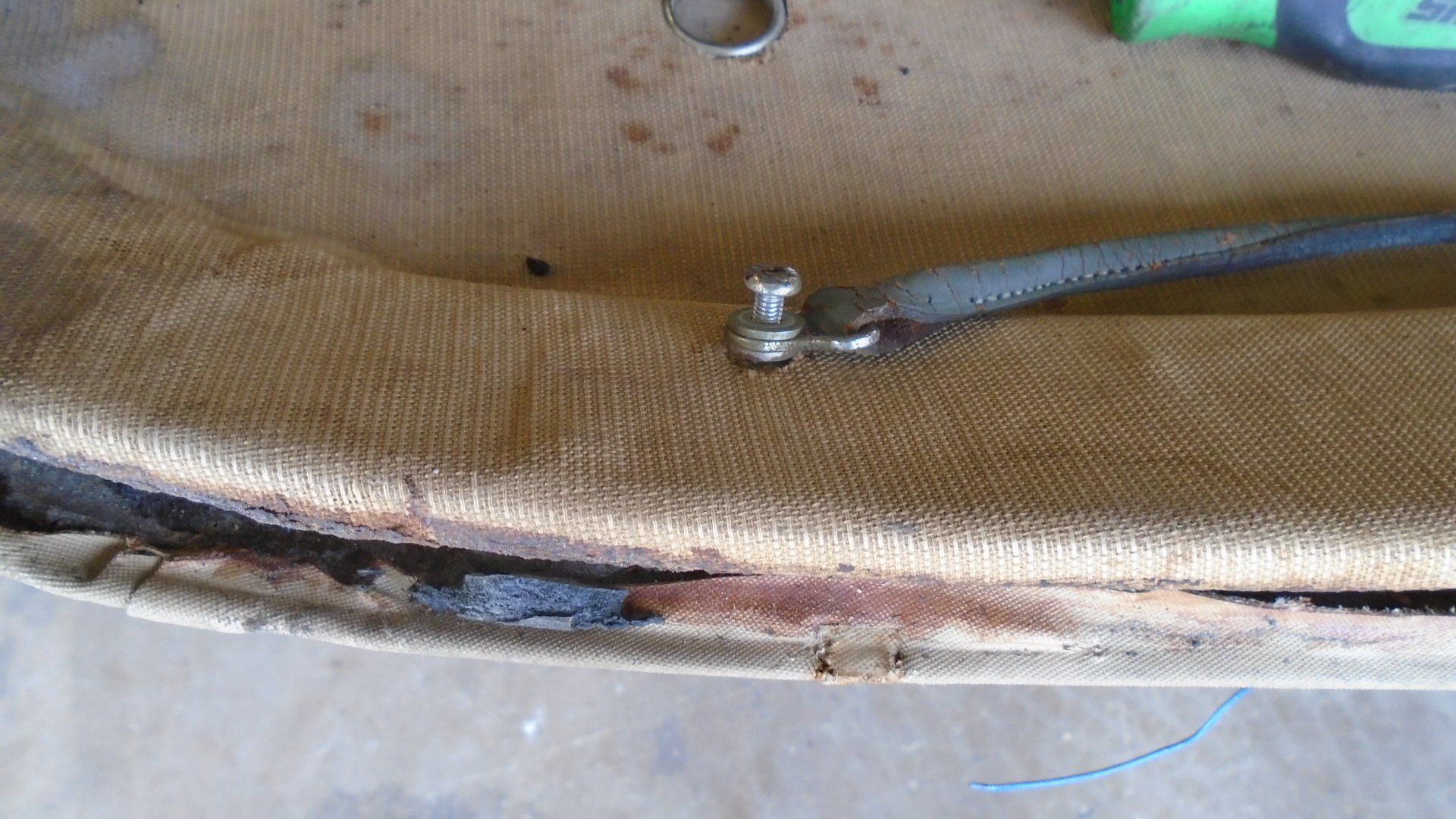 Tan canvas material with metal stud, likely part of a car seat or upholstery.