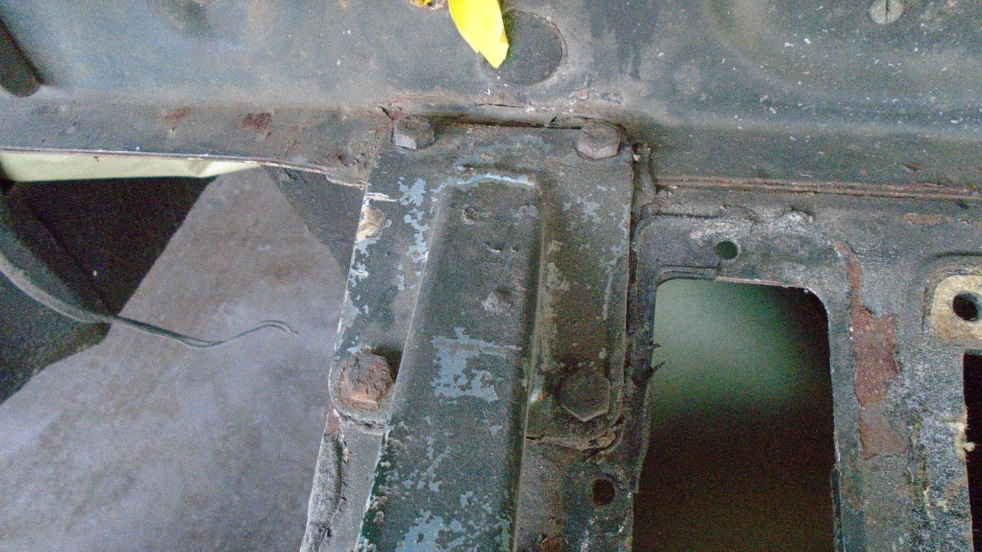 Close-up view of weathered, dark metal framework with bolts, showing signs of rust and wear.