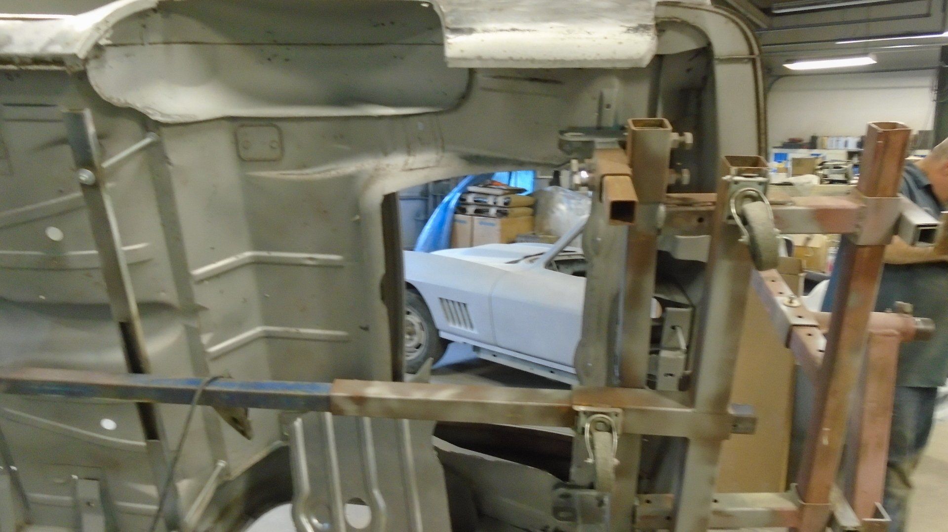 Car body restoration in a workshop, showcasing metalwork and a car in the background.