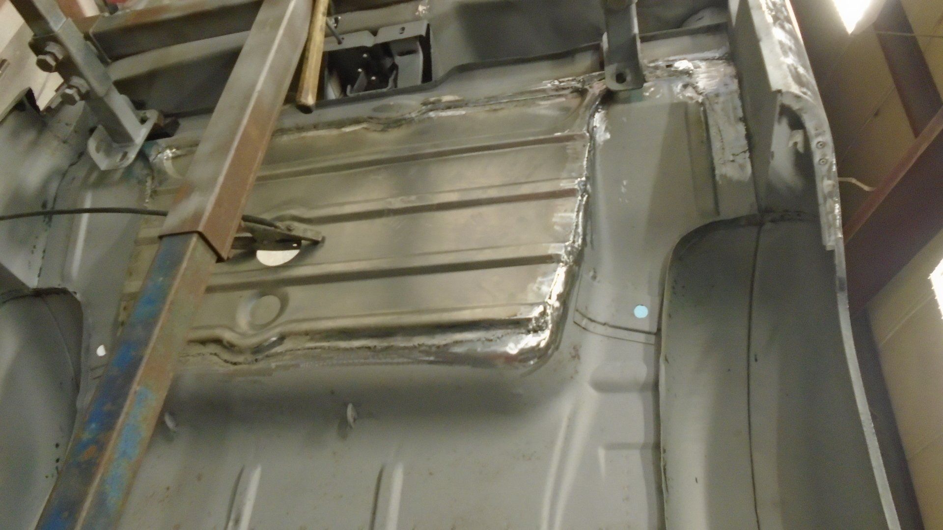 Interior of a vehicle, showing welded metal floor repairs, with support beam.