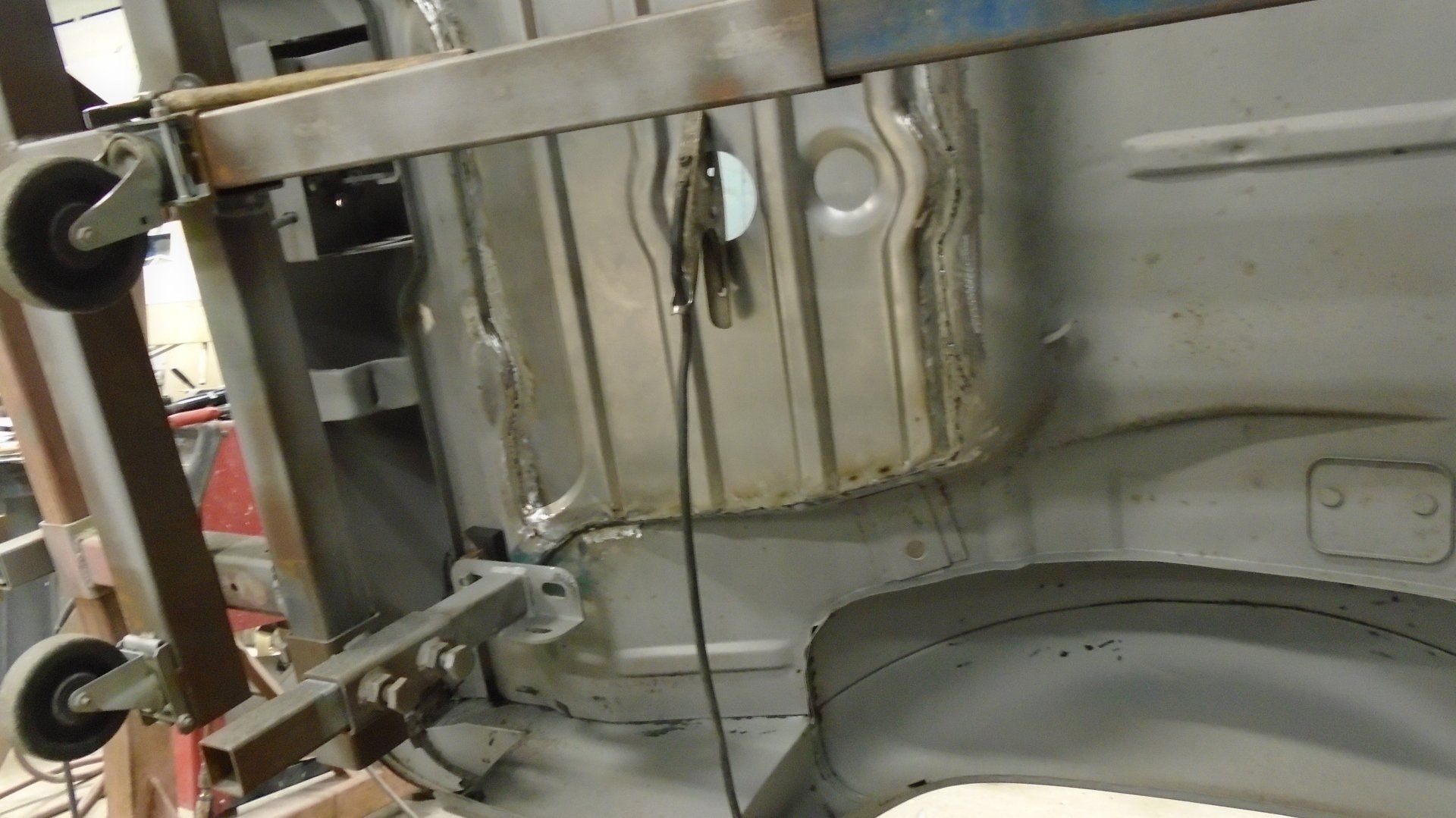 Car chassis section being repaired with a metal support system in a workshop.