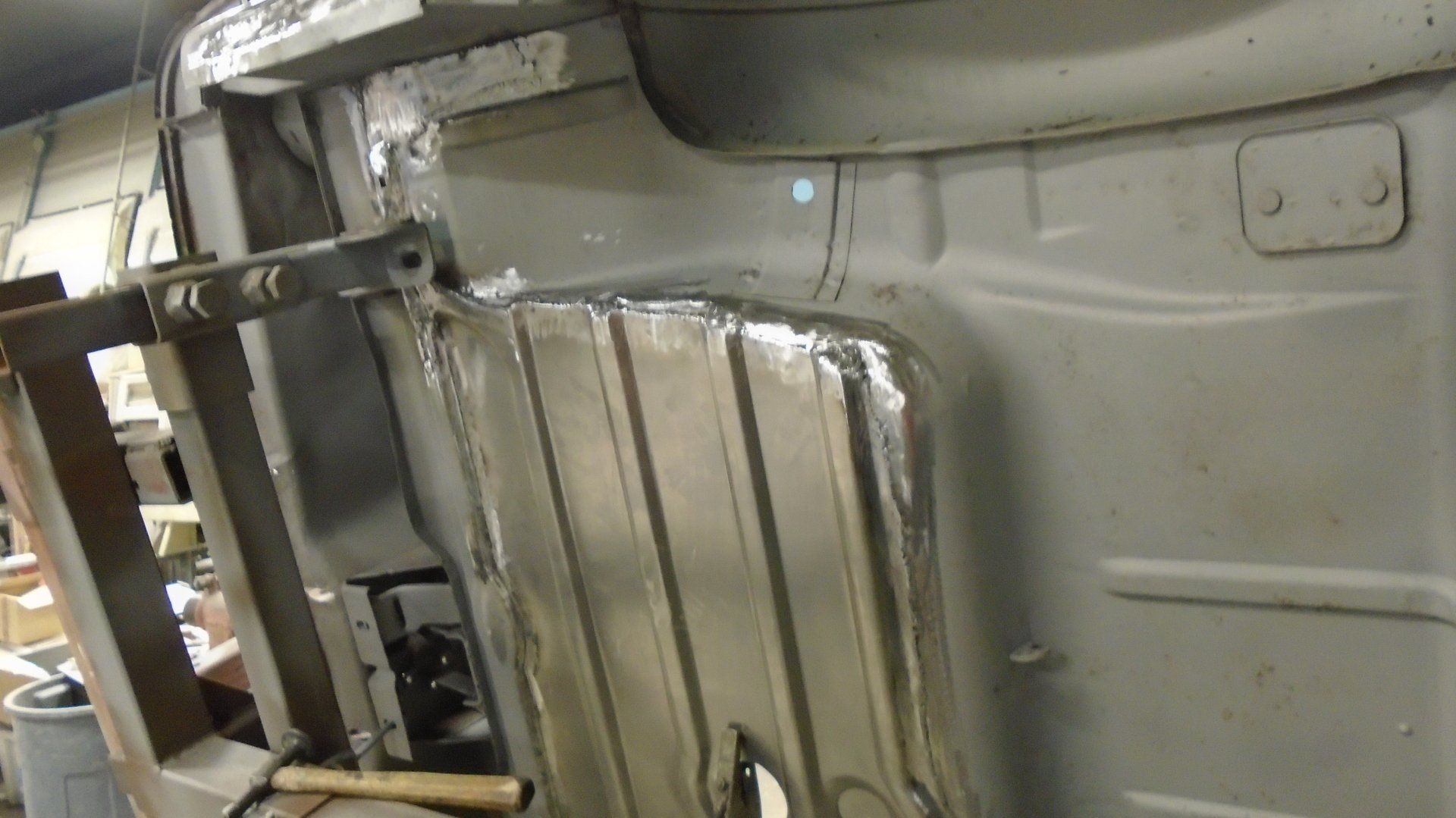 Silver metal car undercarriage being worked on.