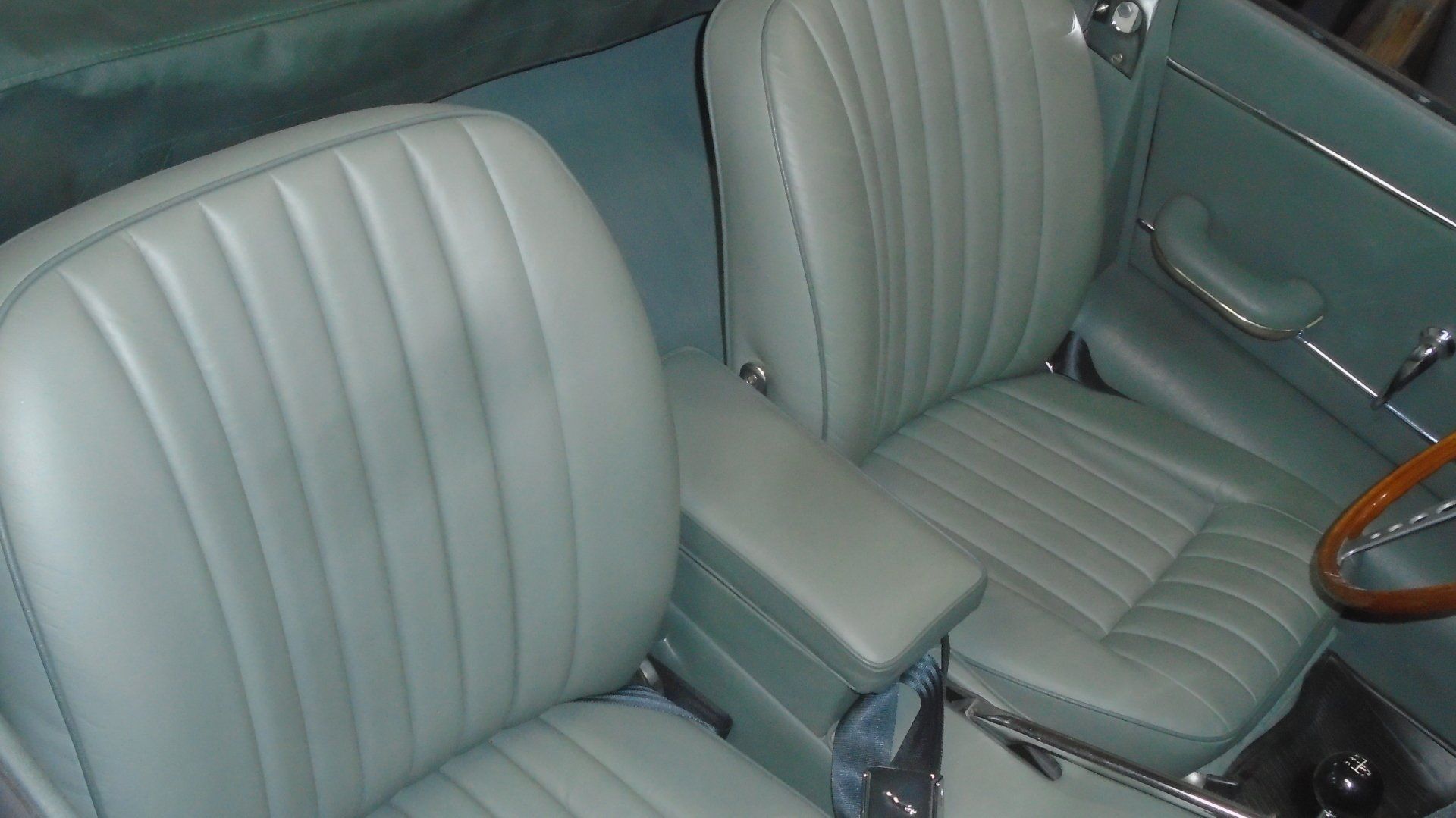 Green leather car interior with vertically ribbed seats and center console.