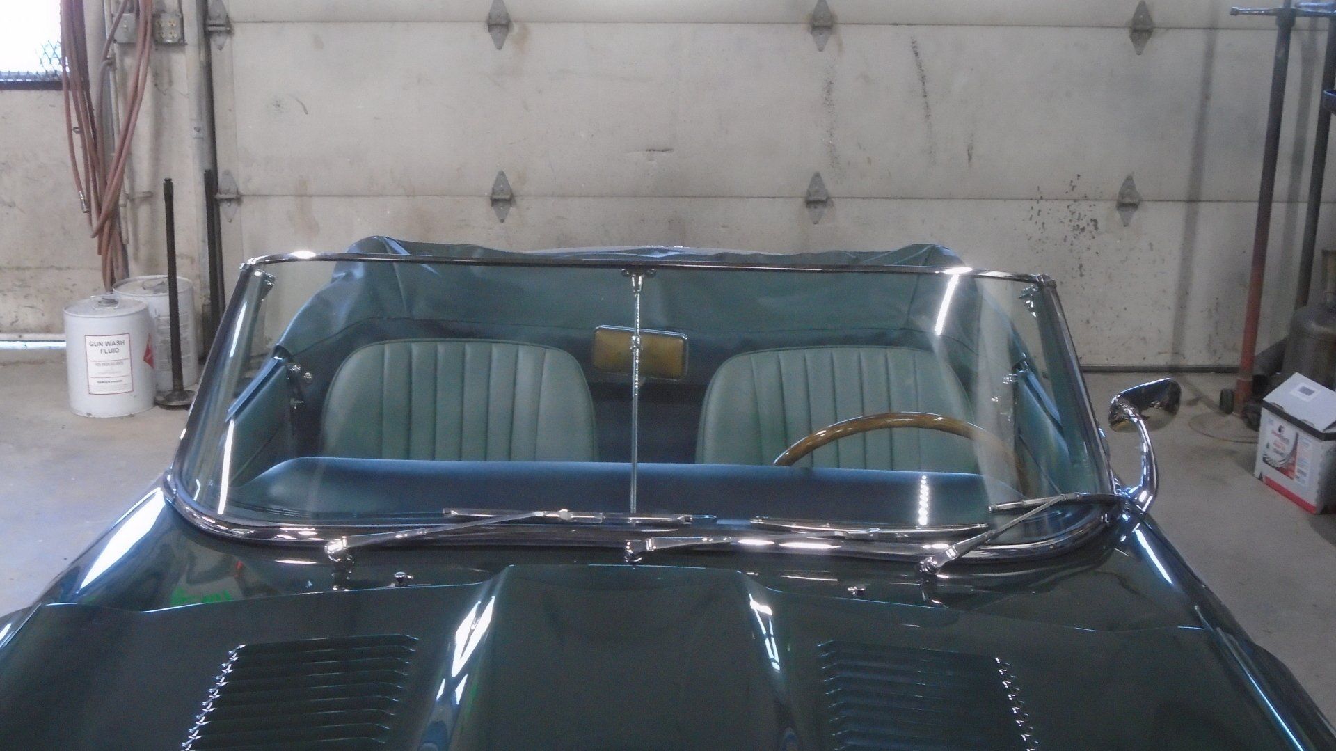 Green classic car interior with blue seats, in a garage.