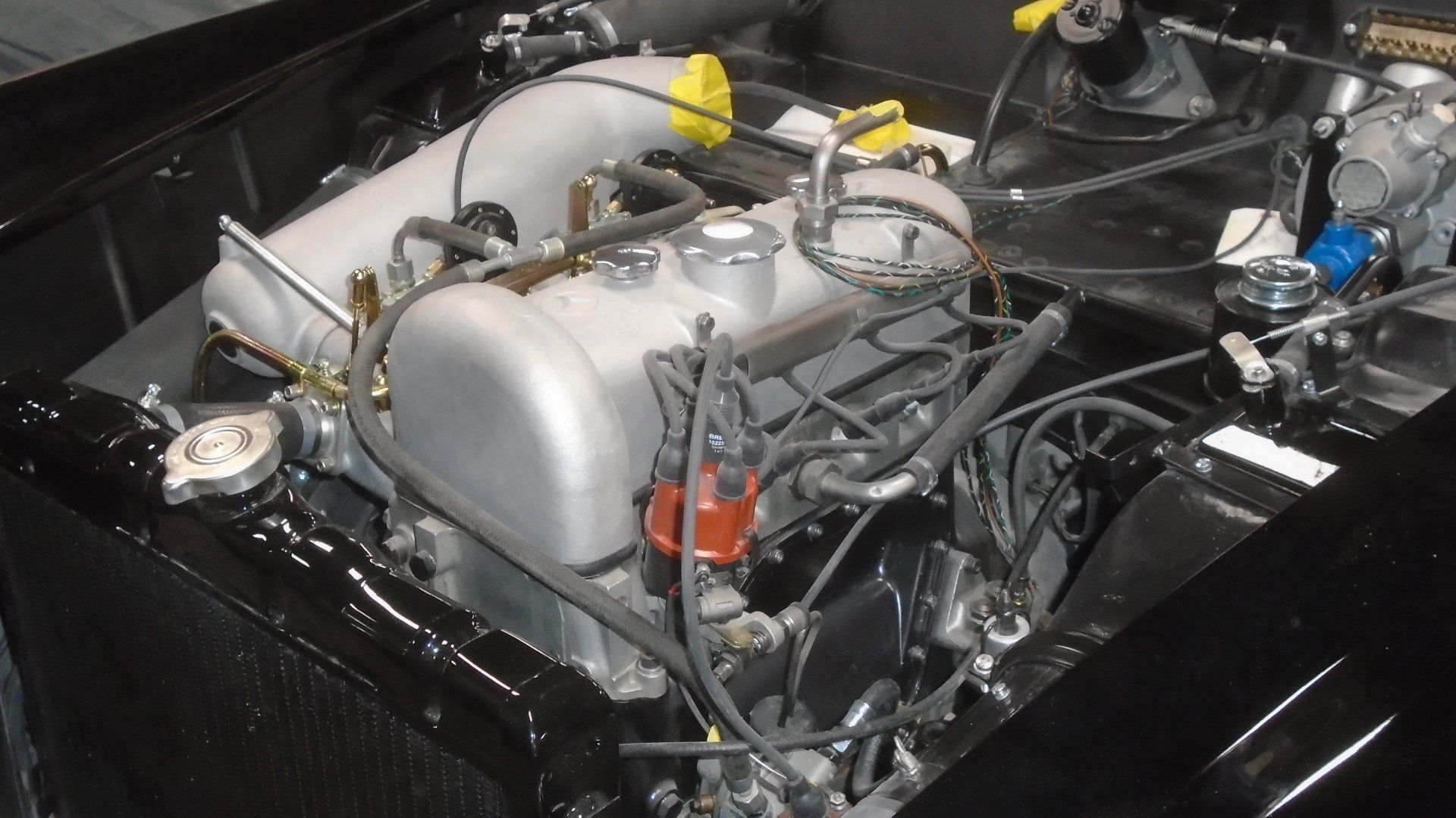 Engine bay of a black car with a silver engine and various mechanical components.