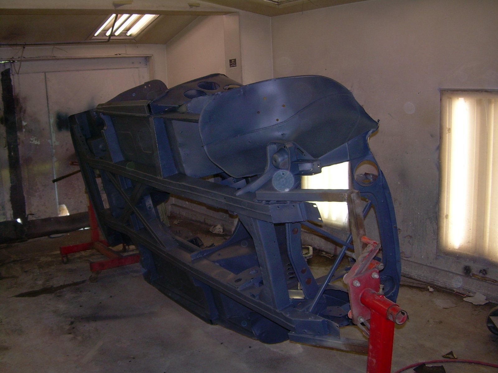 Car chassis on a rotisserie in a spray booth, ready for paint.