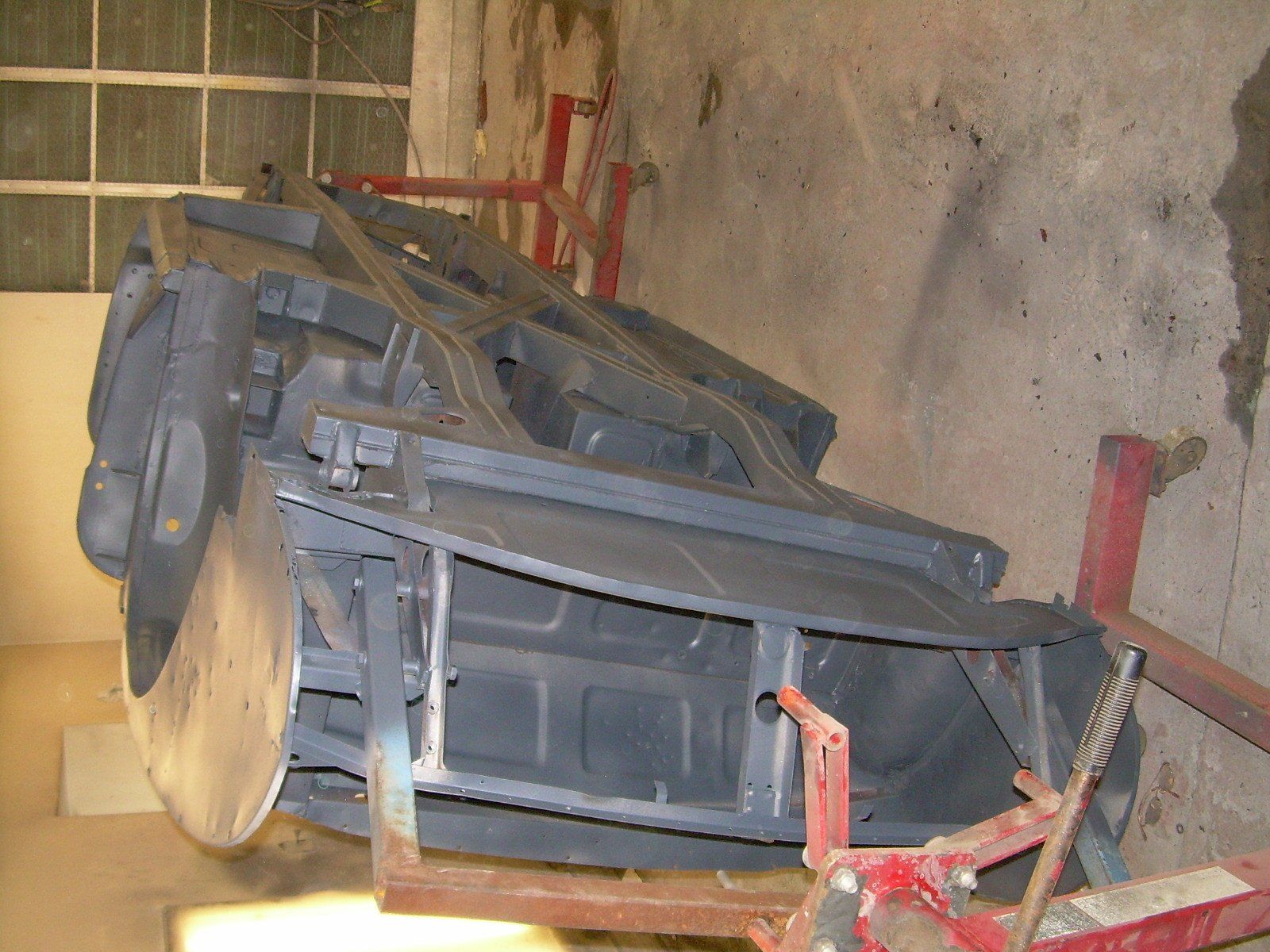 Black car chassis on red stands in a workshop.