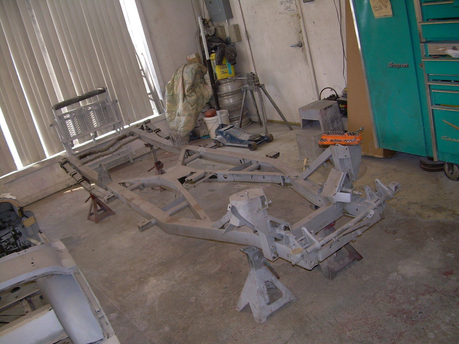 Bare vehicle chassis on jack stands in a garage.