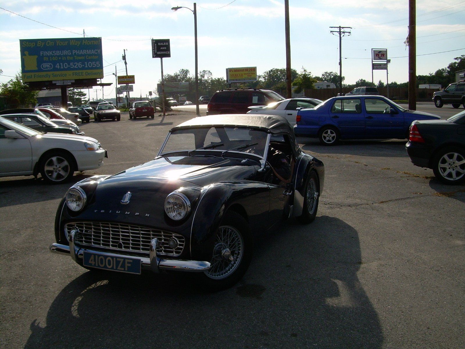 Black Triumph TR3 sports car parked in a car lot on a sunny day.