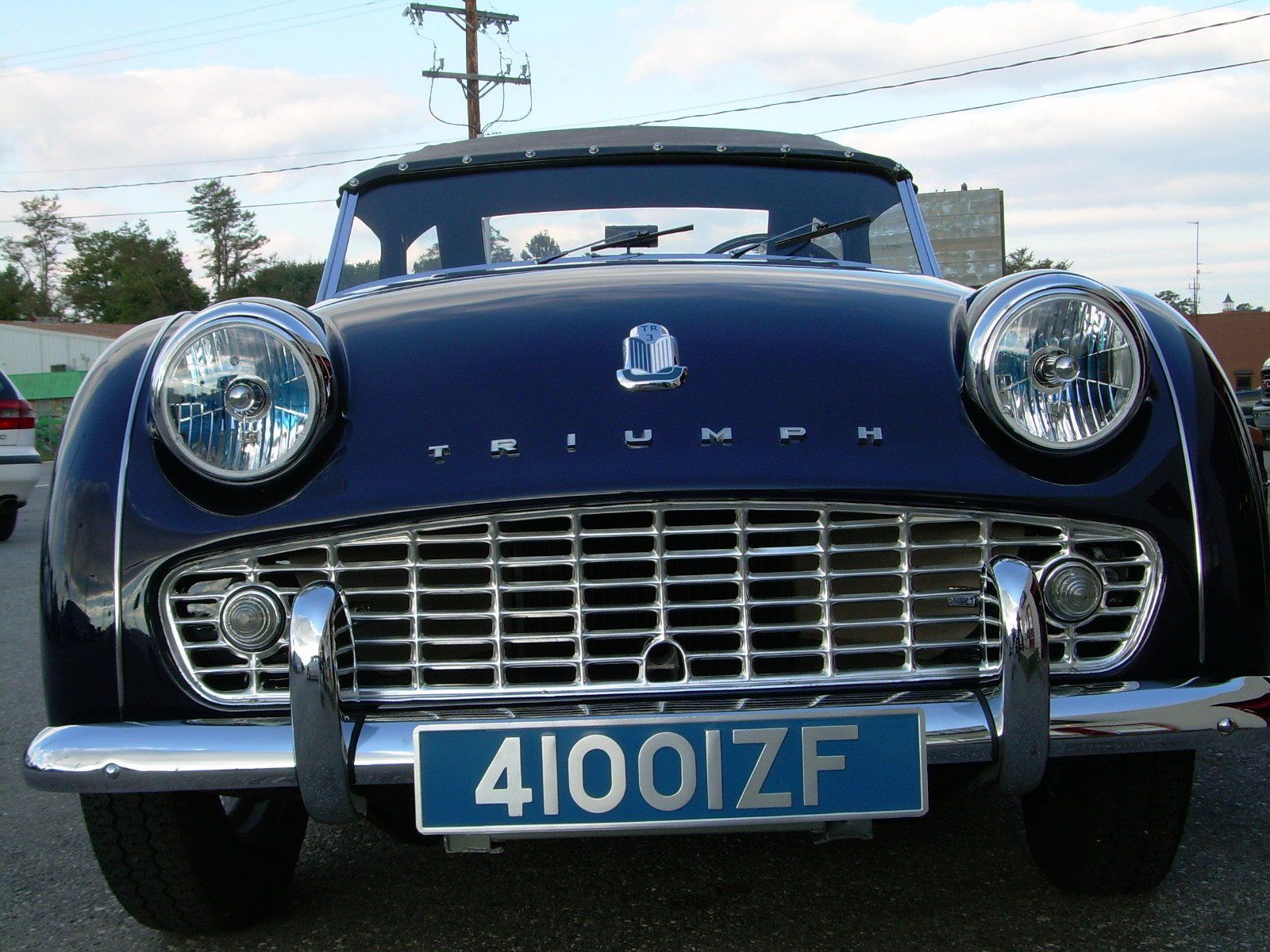 Blue Triumph TR3 convertible car, front view, with chrome details and license plate.