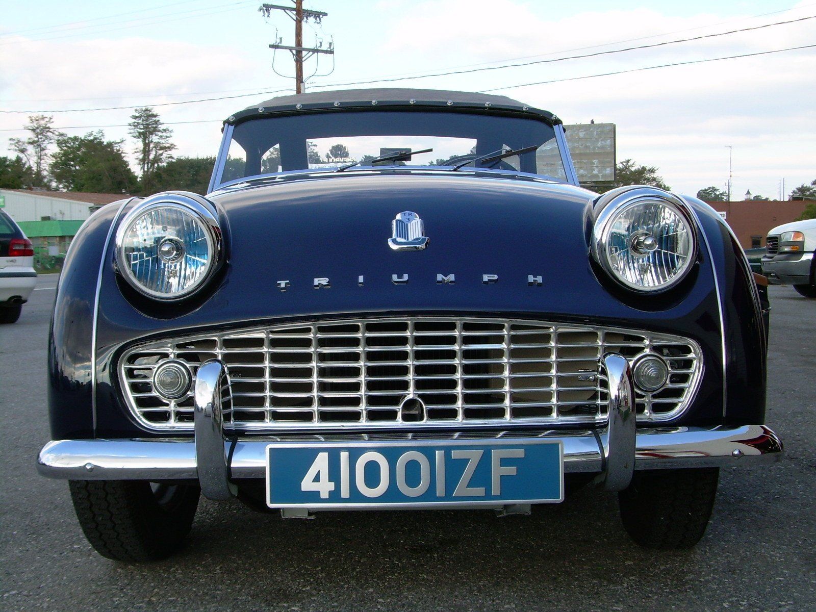 Dark blue Triumph TR3 sports car, front view, chrome grill and bumpers, blue license plate.