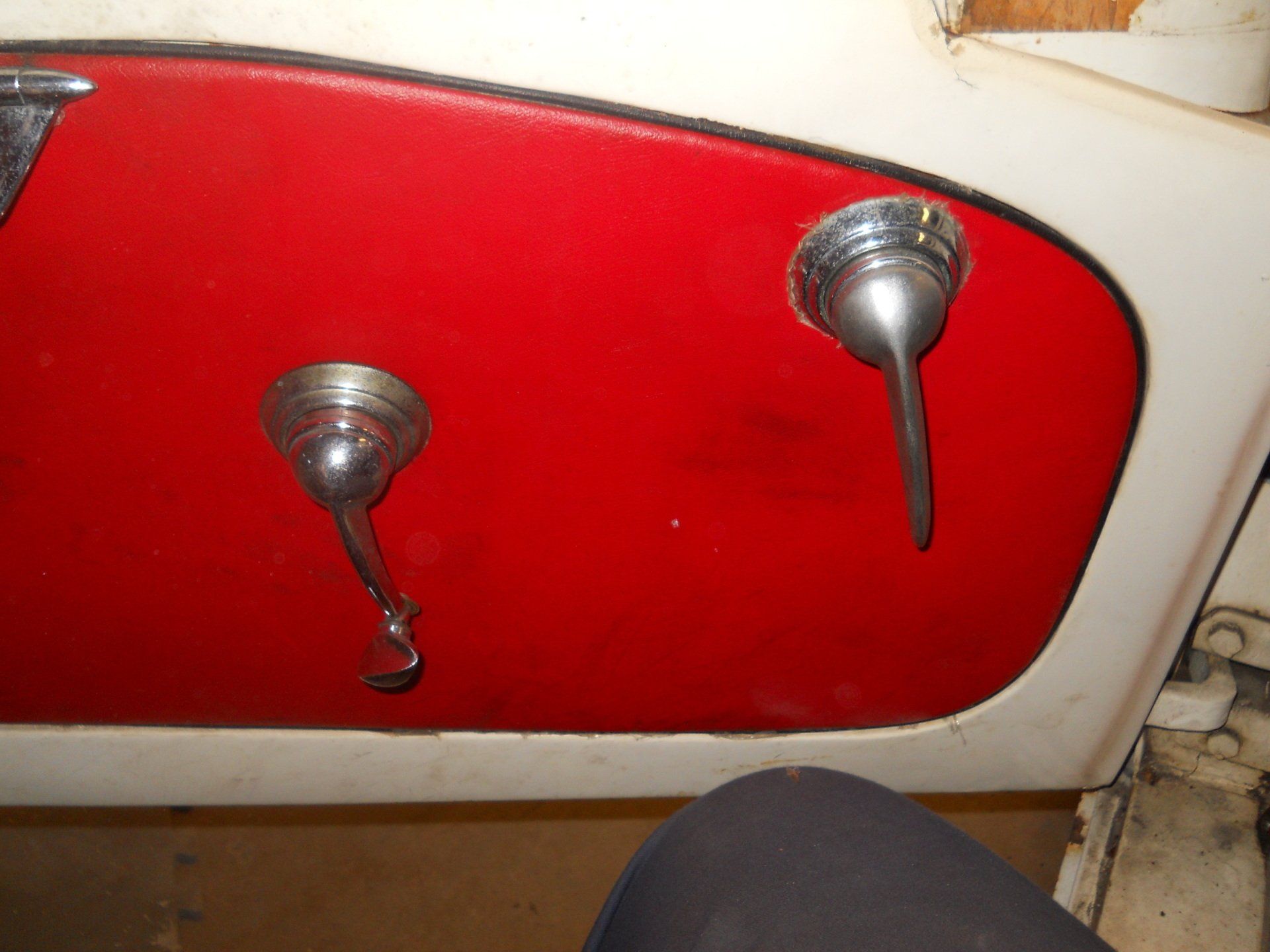 Red car door panel with chrome handles and white trim.