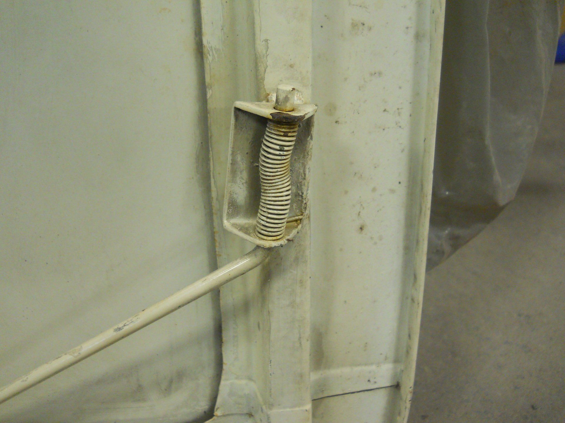 White vehicle door hinge with a visible spring.