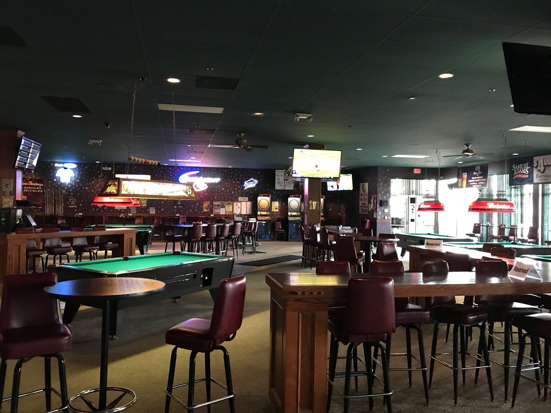 Empty bar or lounge with tables, chairs, neon signs, and dim lighting