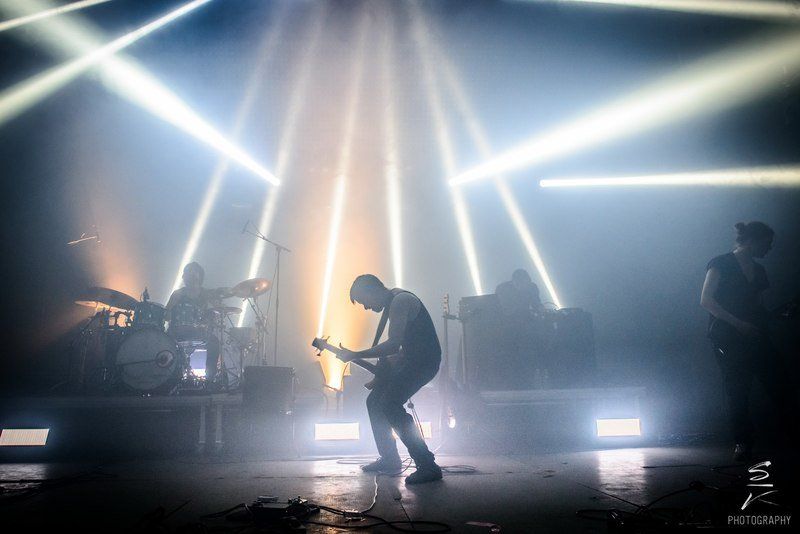 a man is playing a guitar on a stage in front of a crowd .