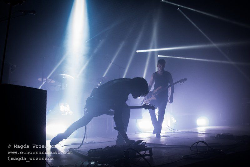 two men are playing guitars on a stage in a dark room .