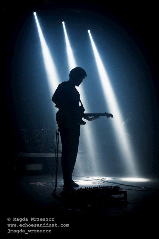 a silhouette of a man playing a guitar in a dark room