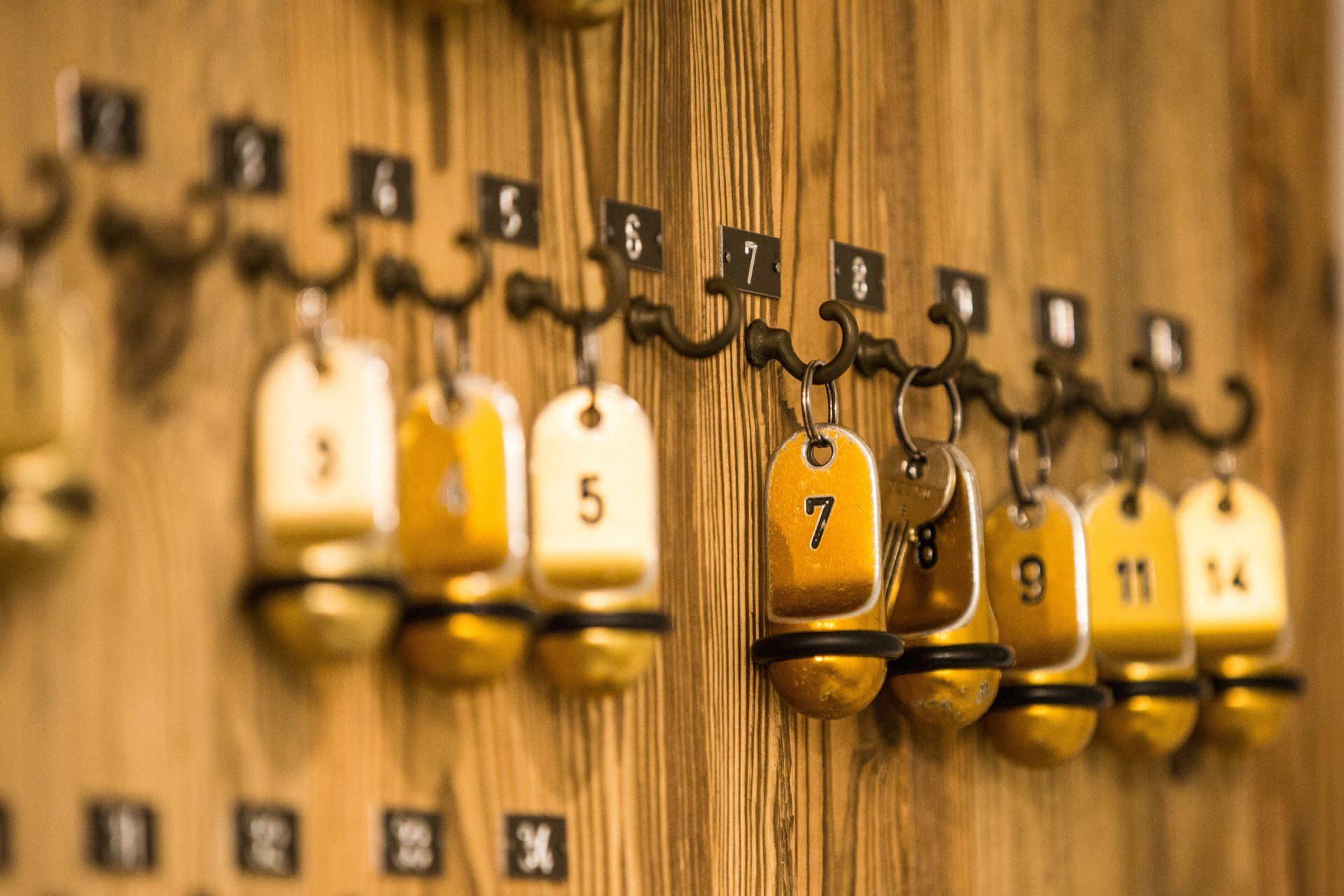 Una fila di chiavi di camere d'albergo appese a una parete di legno.
