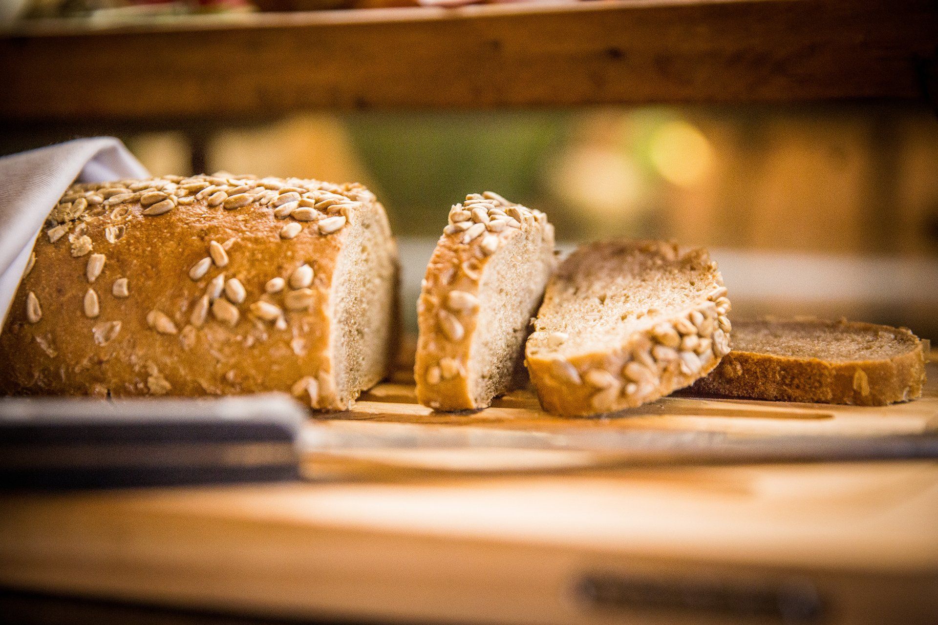 Una pagnotta di pane con semi di girasole è appoggiata su un tagliere di legno.