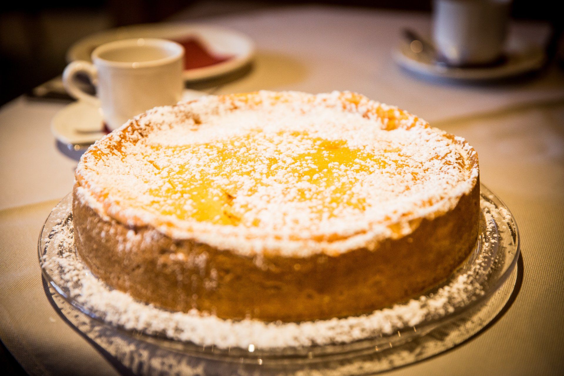 Una torta ricoperta di zucchero a velo è posta su un piatto di vetro su un tavolo.