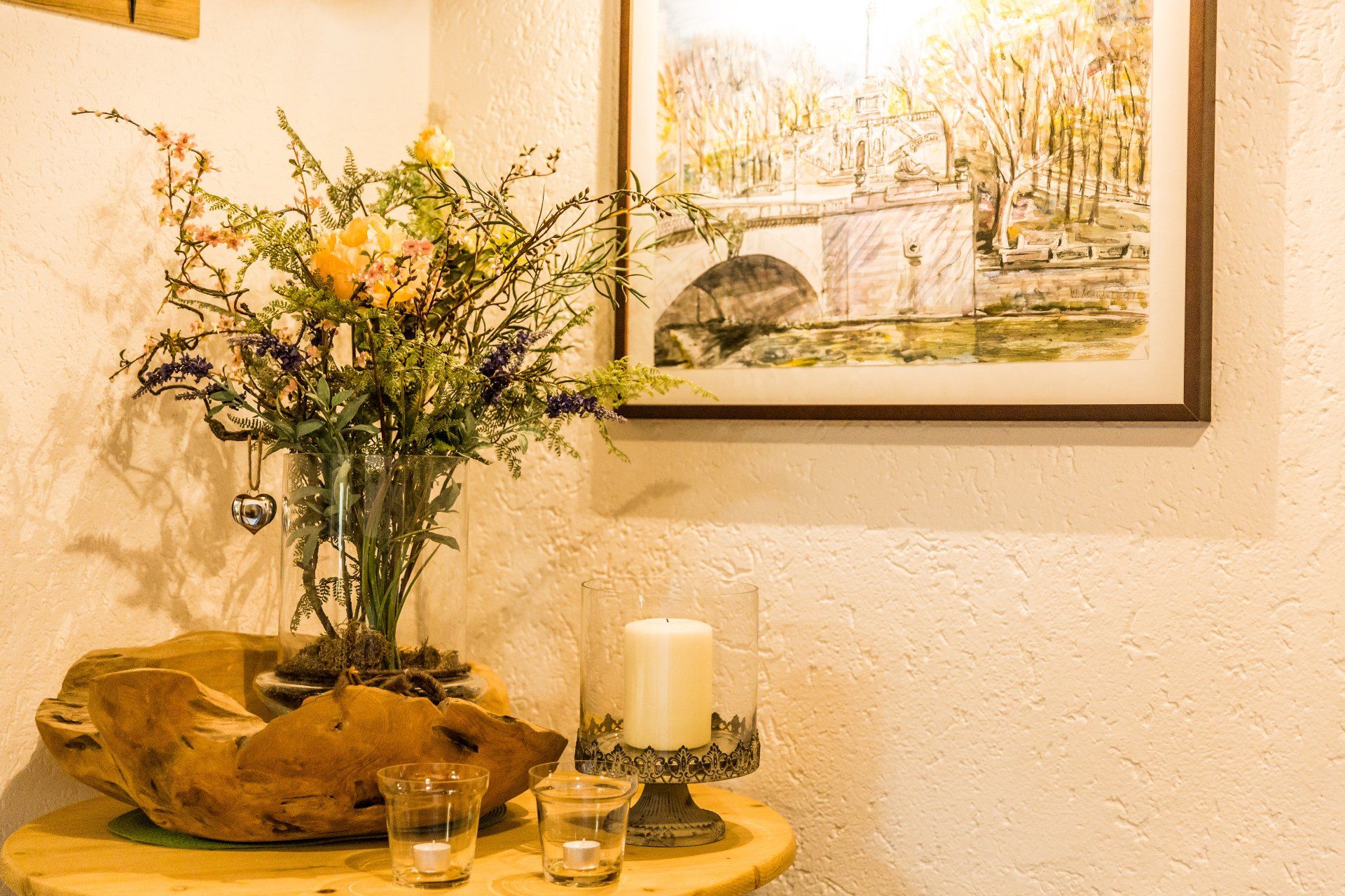 Un tavolo con un vaso di fiori e una candela sopra.